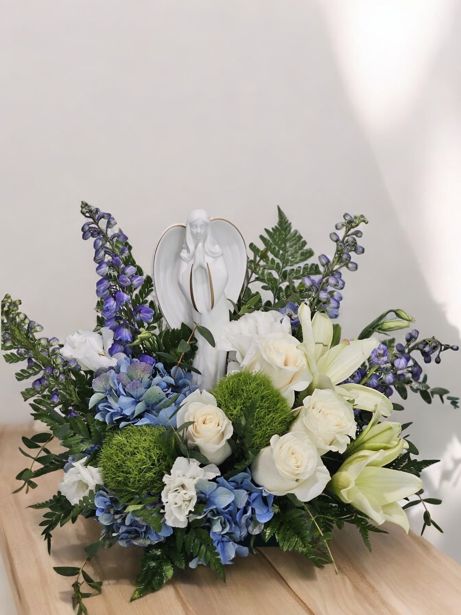 Angelic Serenity - This Arrangement evoke a sense of tranquility and reverence, fitting for an arrangement with an angelic theme and a harmonious blend of colors and flowers is made with Blue Delphium, Blue Hydrengas, white Lisianthus, white Roses, White Lilies with Greenery&nbsp;&nbsp;