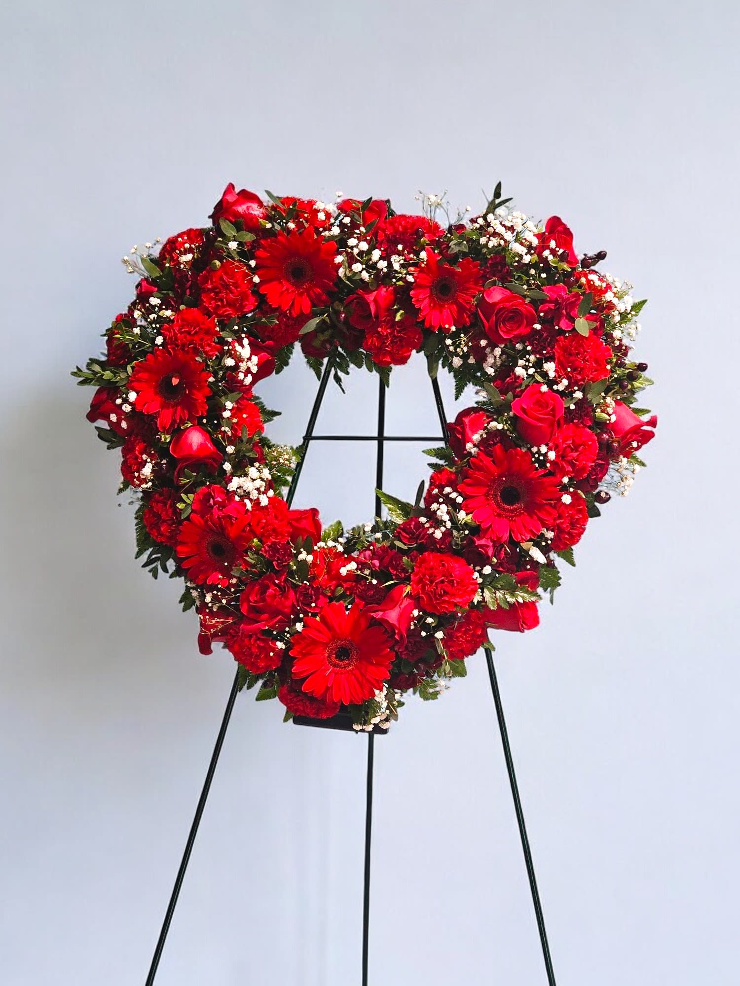 Eternal Remembrance - Eternal Remembrance is a beautiful tribute to celebrate a life well lived. This arrangement features a heart made of all red flowers including gerberas, roses, carnations, and minicarnations, highlighted with delicate white gyp and lush greenery. Delivered on an easel for a thoughtful display.