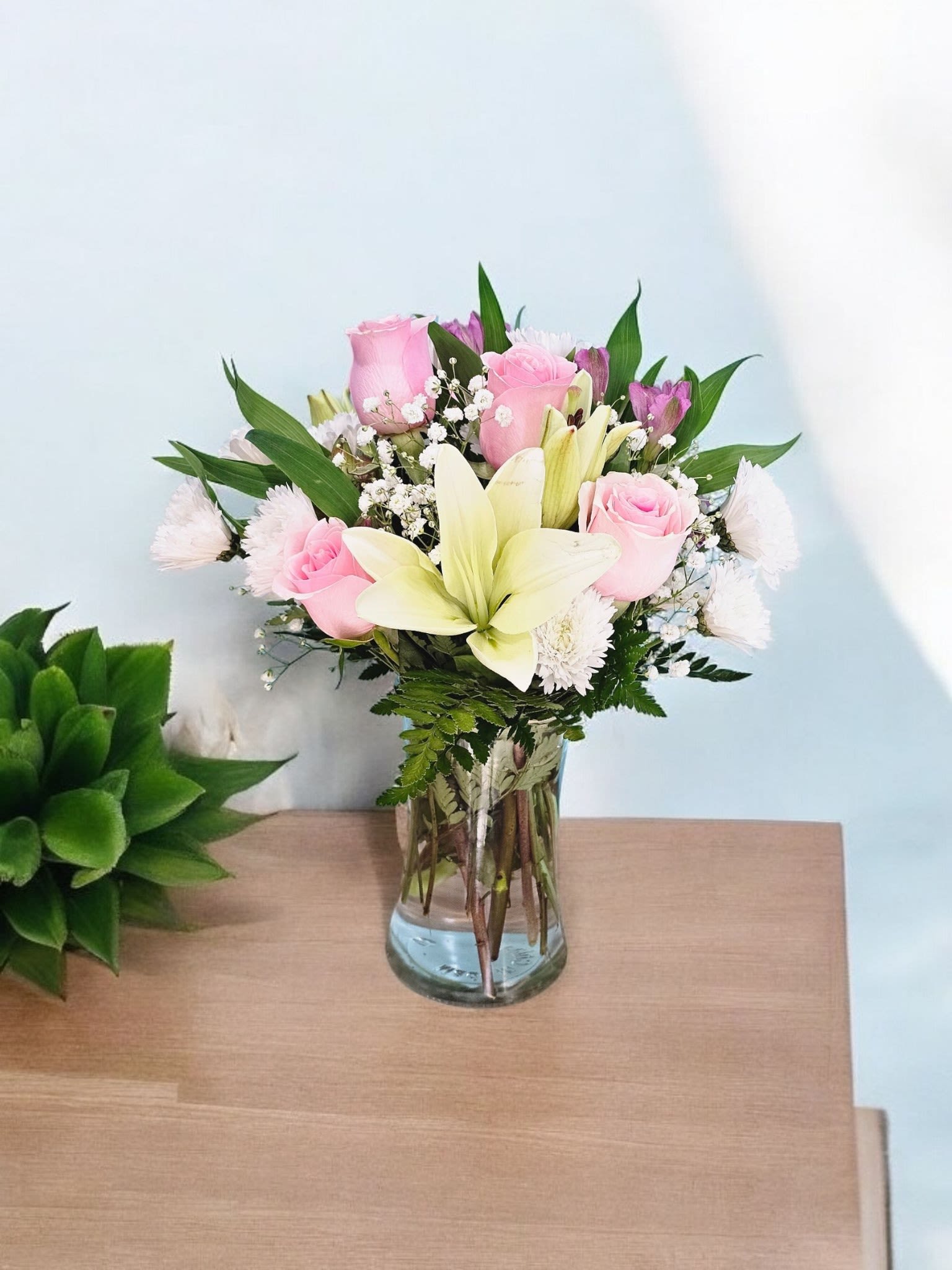 Blushing Serenity - Experience pure serenity with our Blushing Serenity bouquet. Delicate white lilies, pink roses, and lavander alstromeria combine with white cushion, gypsophila, and fine greenery in a clear vase. Perfect for adding a touch of elegance and tranquility to any space.