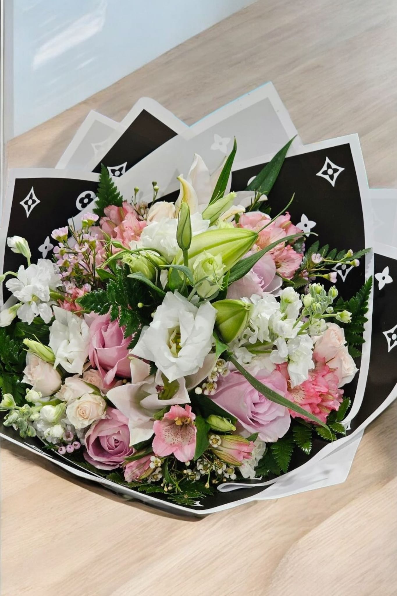 Blush Mix flowers Bouquet - This elegant bouquet features a mix of assorted blush flowers, including lilies, roses, spray roses, alstromeria, lisianthus, stock, and fine filler. Wrapped in beautiful paper, it adds a touch of sophistication and beauty to any occasion. The perfect gift for your loved ones.