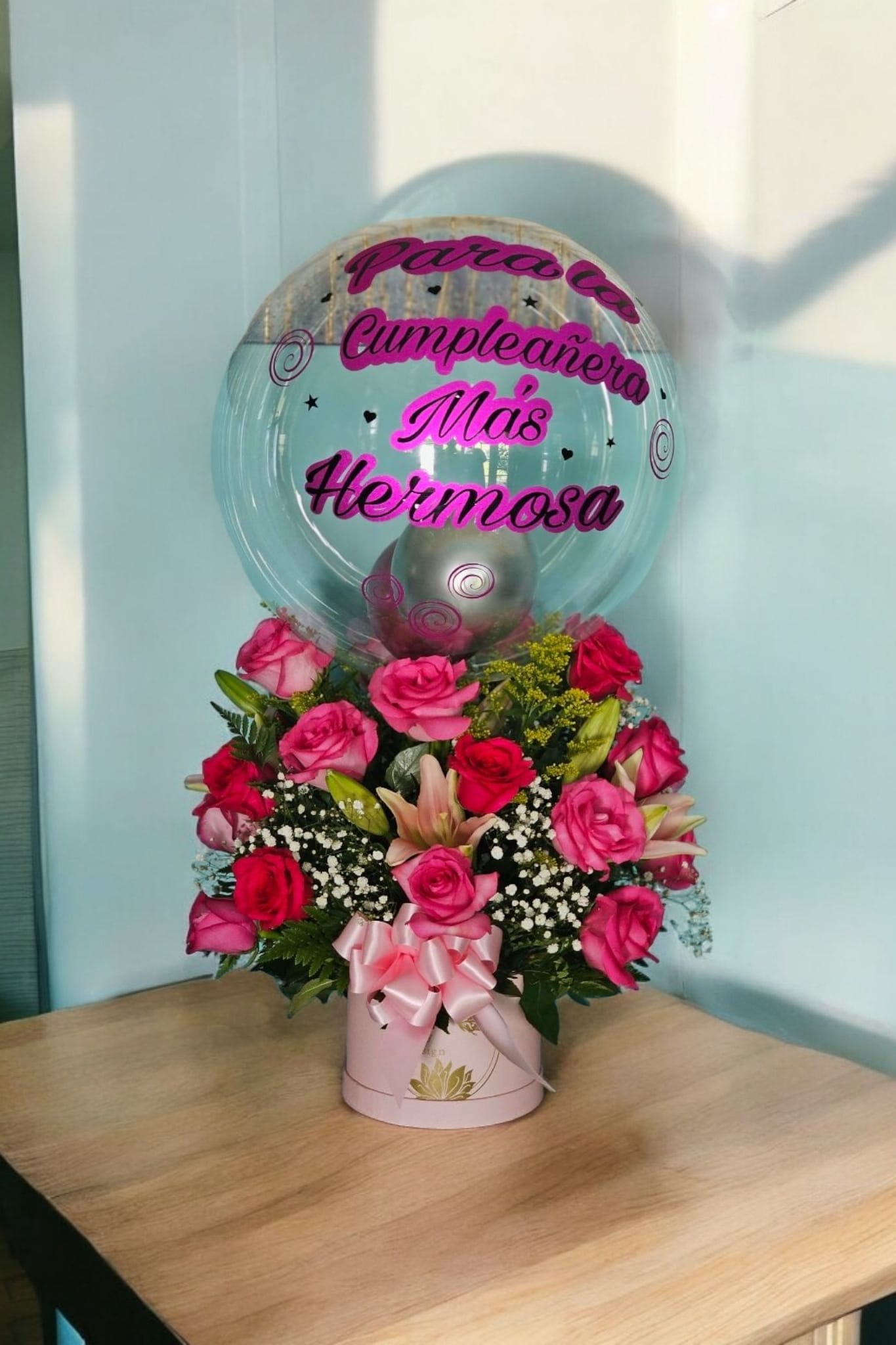 Blush Harmony - This elegant arrangement boasts a pink box with a personalized balloon, filled with beautiful pink and hot pink roses, lilies, and fine filler. Accented with lush greenery and a delicate pink ribbon, this bouquet is sure to make a statement.