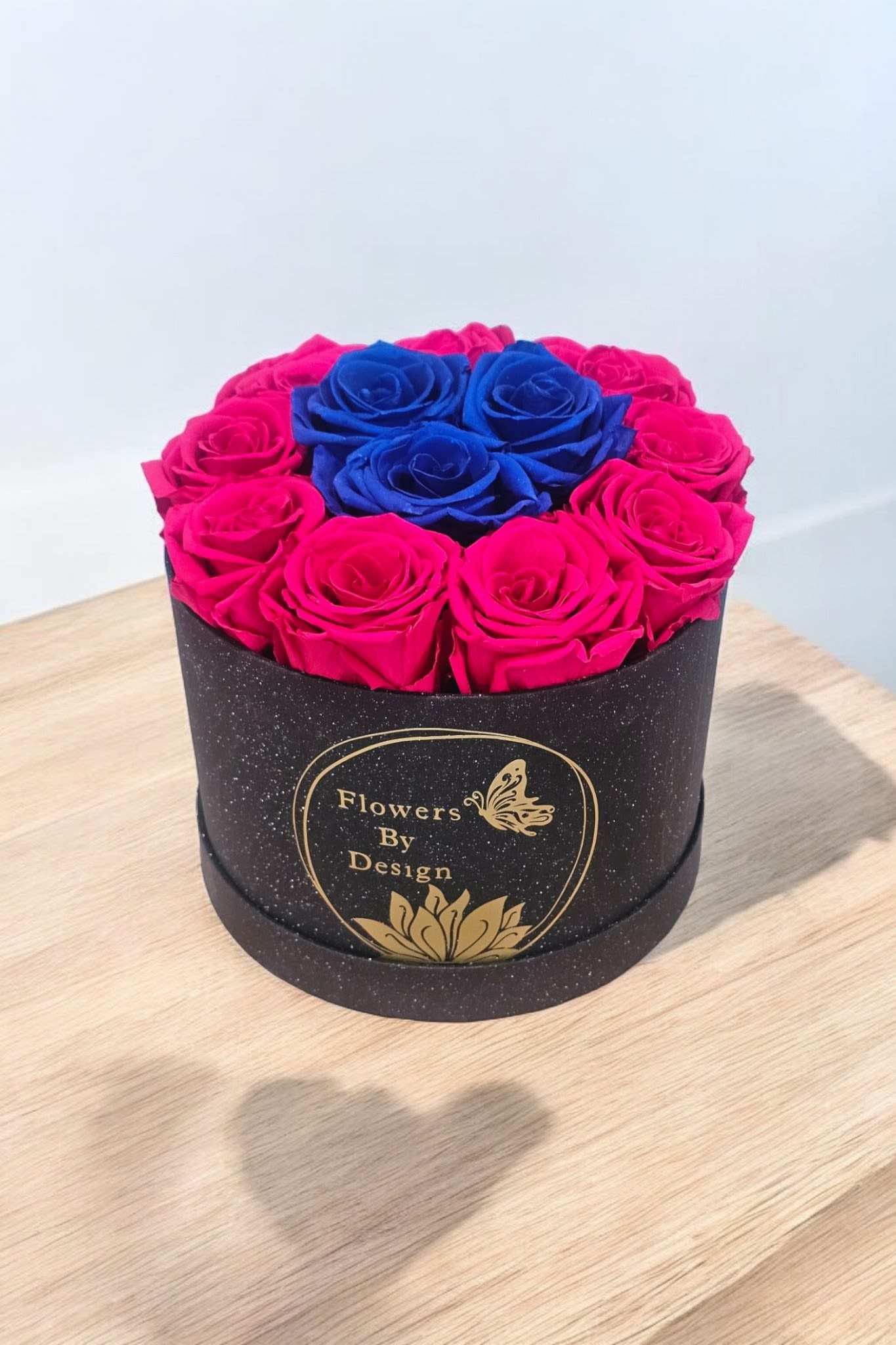 Midnight Luxe Roses - The sophistication of the black box and the striking contrast of fuchsia and blue preserved roses. This arrangement is made with Nine Hot Pink Roses and Three Blue Roses. if you take good care of them, they can last up to three years.