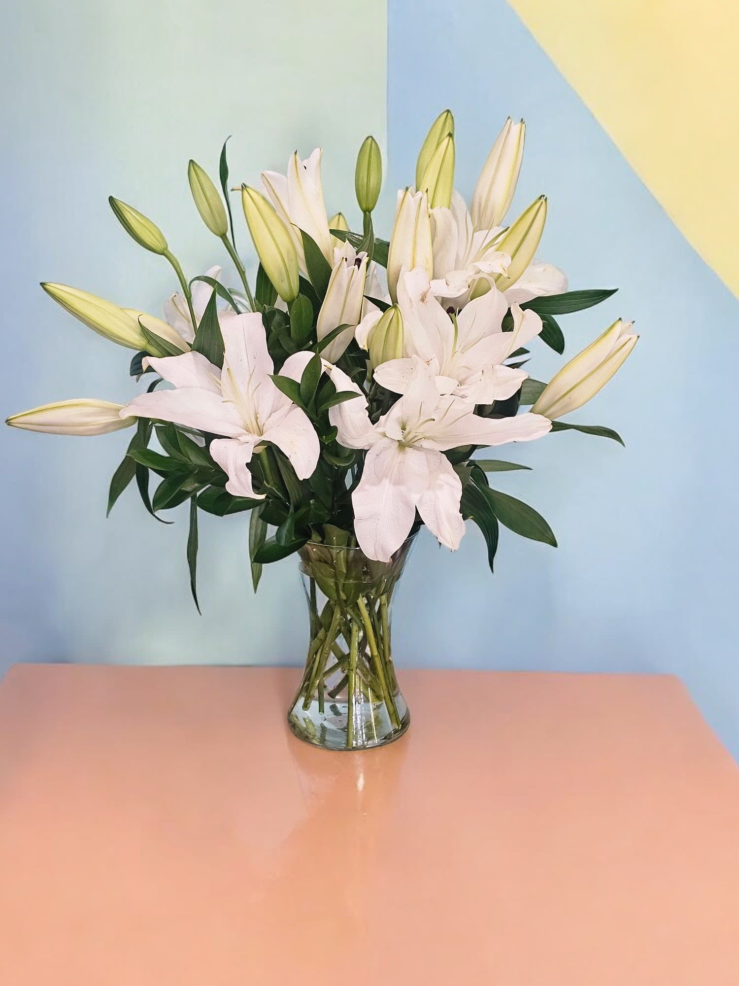 Elegant Whites - This Arrangement reflect the sophisticated and serene nature of the arrangement, emphasizing the purity and grace of the white blooms and the delicate greenery. This Arrangement is made with White oriental Lilies and fine greenery.