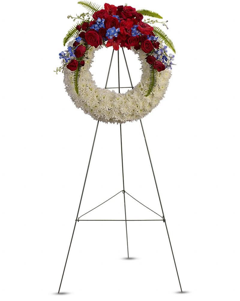 Standing wreath of white flowers with red roses and blue blooms on a metal easel