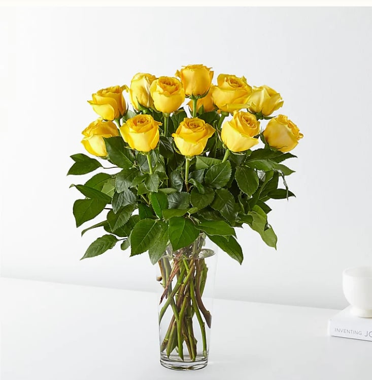 Tall bouquet of yellow roses arranged in a clear glass vase.