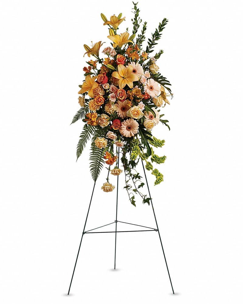 Tall standing spray of yellow lilies, roses, and peach gerberas on a metal easel