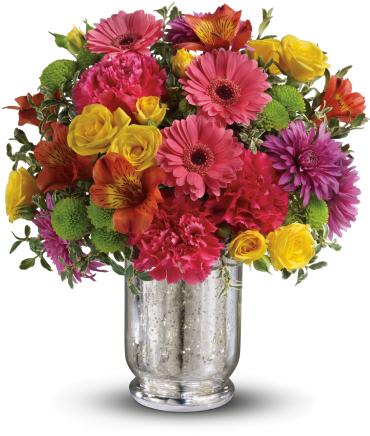 Bright mixed bouquet of pink gerbera daisies, yellow roses, and green buttons in a silver glass vase