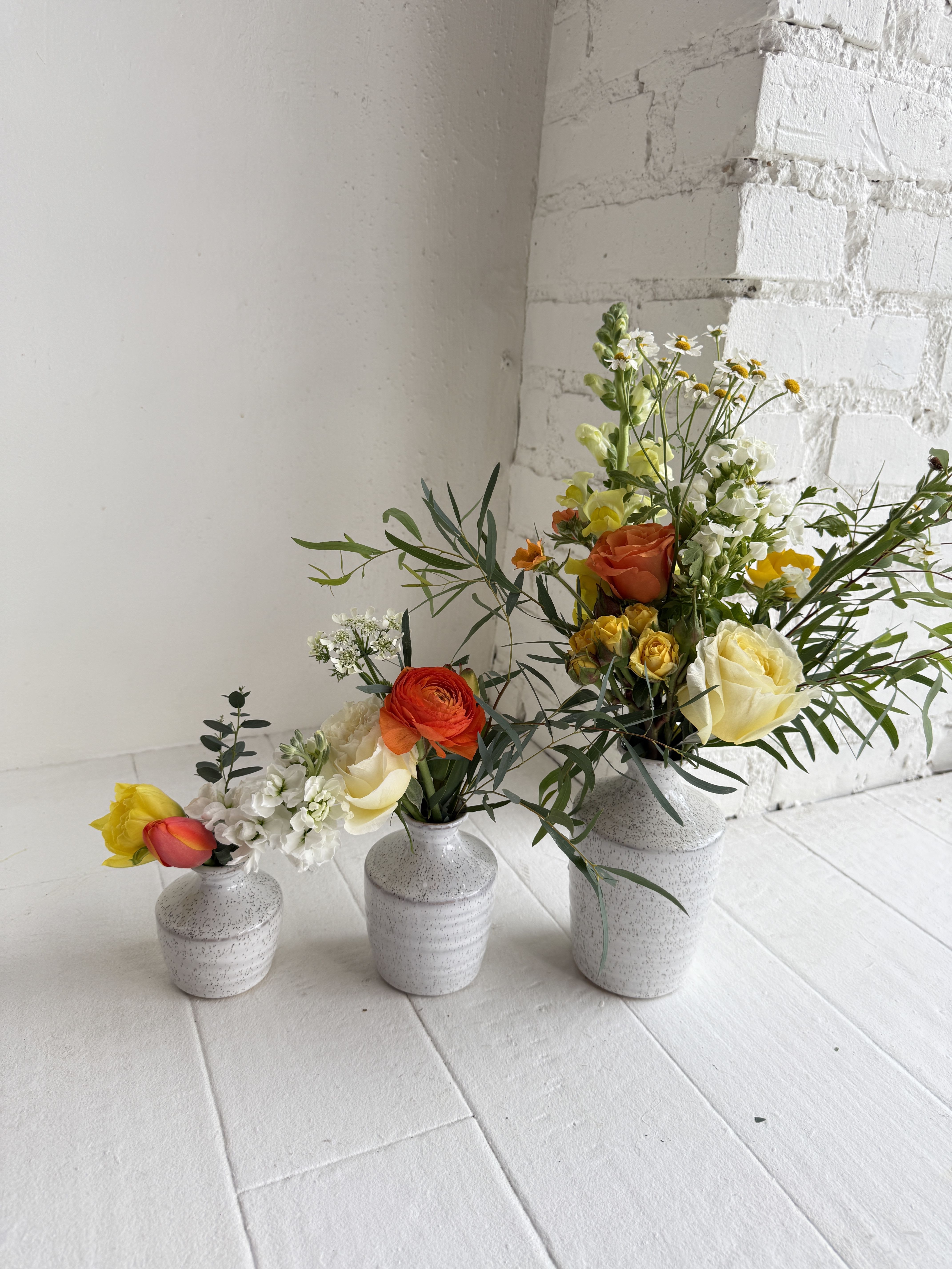Cleo - Beautiful blooms in shades of orange, yellow and white in a set of three vases. We love the flexibility of Cleo. The vases can be placed together as a group, or divided and placed around the home or office for maximum enjoyment. We use an eclectic mix of our best seasonal flowers.