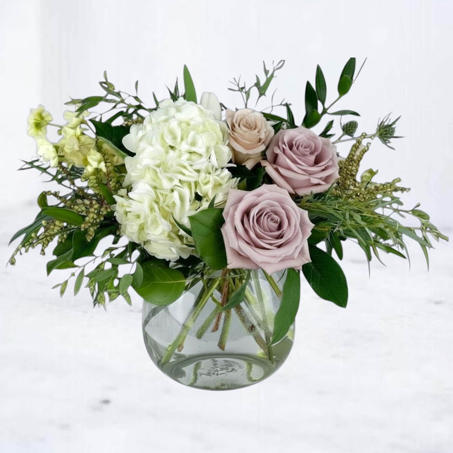 Stone &amp; Silk - Refined, modern, and effortlessly elegant, Stone &amp; Silk is a luxury flower arrangement designed for those who appreciate understated beauty. Featuring soft taupe roses, lush white hydrangea, and airy seasonal greenery, this arrangement creates a serene, balanced look that feels both elevated and natural.  Designed in a clear glass vase, Stone &amp; Silk highlights the organic movement of each stem while maintaining a clean, structured silhouette. The muted palette of soft neutrals and fresh greens makes this arrangement incredibly versatile—perfect for sending a thoughtful gift without overwhelming color.  We proudly offer same-day flower delivery in Magnolia, TX and surrounding areas, including The Woodlands, Montgomery, Conroe, Spring, and Tomball. Every arrangement is handcrafted with attention to detail to ensure it arrives fresh, balanced, and beautifully presented.  If you’re looking for a modern florist in Magnolia TX that specializes in elevated, neutral floral designs, Stone &amp; Silk is a perfect choice. Its soft color palette and sculptural composition make it a standout piece that complements any space without overpowering it.  Same-day delivery is available when you order before our daily cutoff time. Each delivery is carefully coordinated to ensure a seamless and professional experience.  Due to seasonal availability, some blooms may be substituted with similar varieties of equal or greater value while maintaining the overall look and feel of the arrangement.