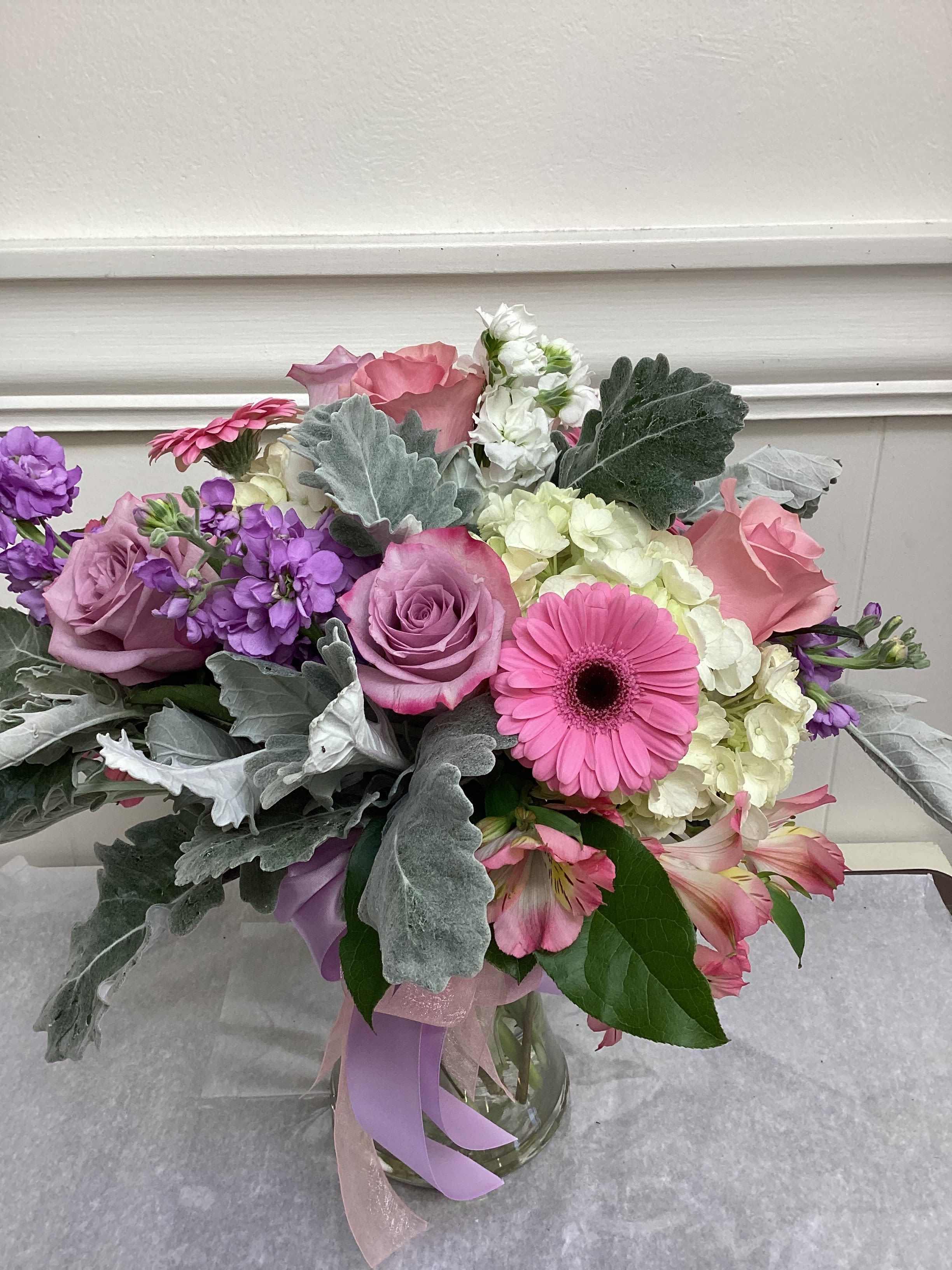 Pastel Paradise - Beautiful pastel blooms in a clear or pink vase.  Includes roses, gerbera daisies, hydrangea, and stock.  