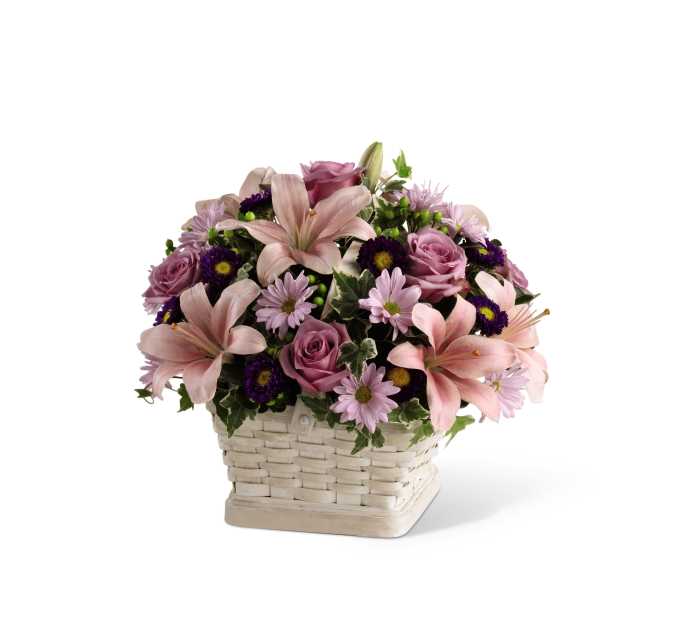 Pink lilies, roses, and purple daisies arranged in a white woven basket