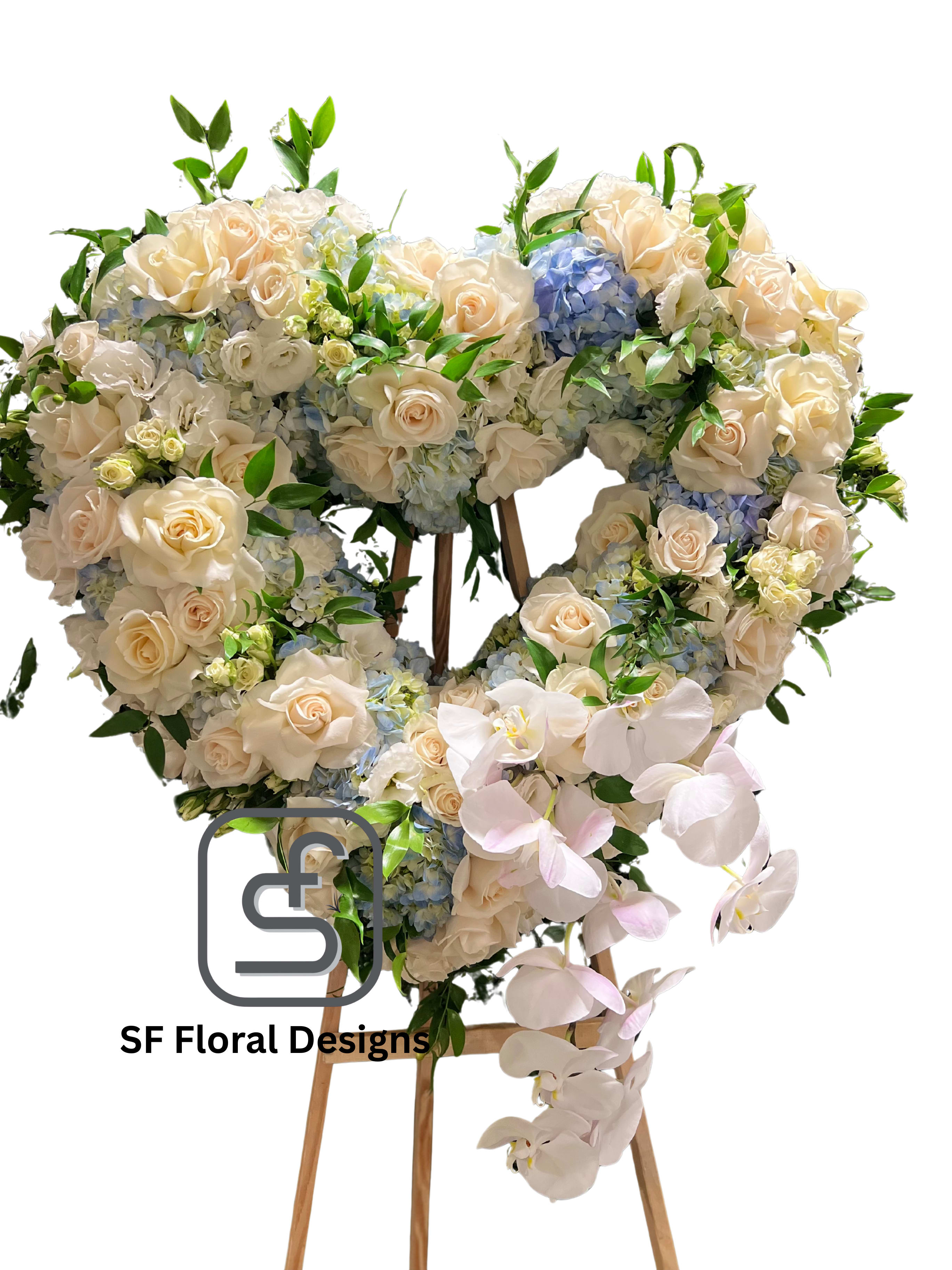 Heart-shaped standing arrangement of cream roses, blue hydrangeas, and cascading white orchids on a wooden easel.