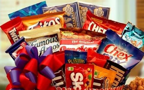 Gift basket filled with assorted snack and candy bags topped with a red and purple bow