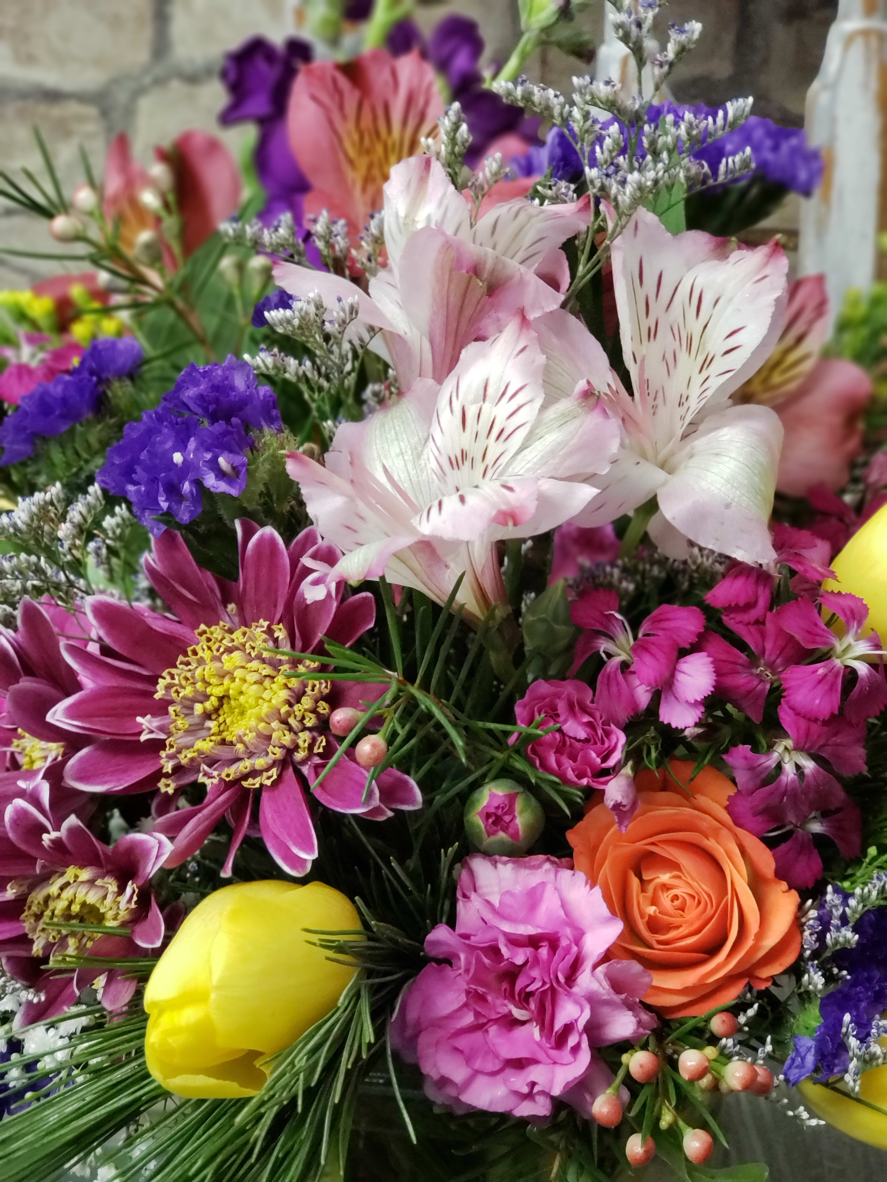Colorful mixed bouquet with pink alstroemeria, orange rose, yellow tulip, and purple mums.