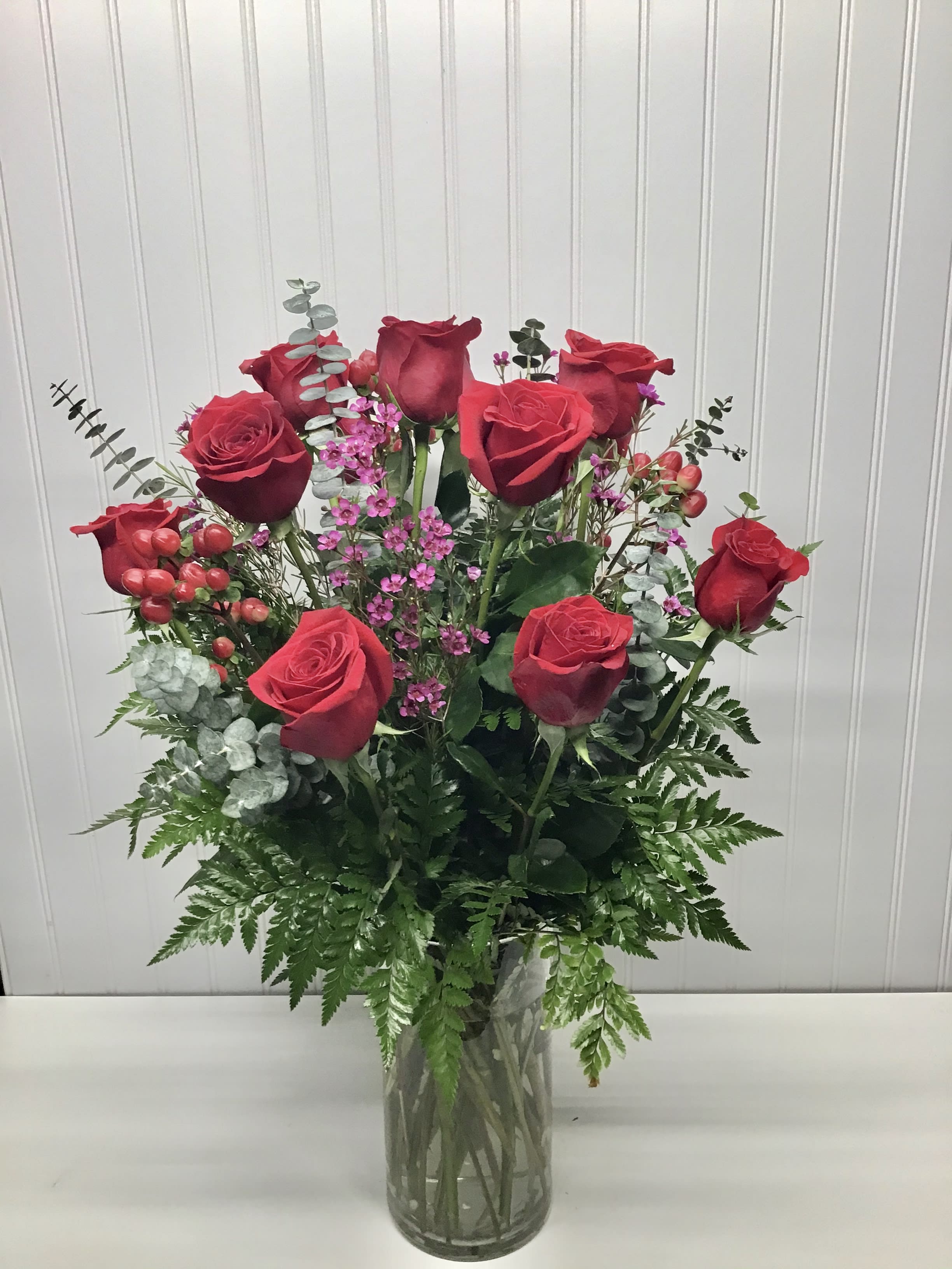 Tall arrangement of red roses with small pink blooms in a clear glass vase