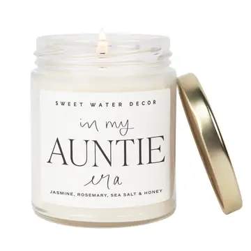 White candle in a glass jar with a gold lid and label for an aunt