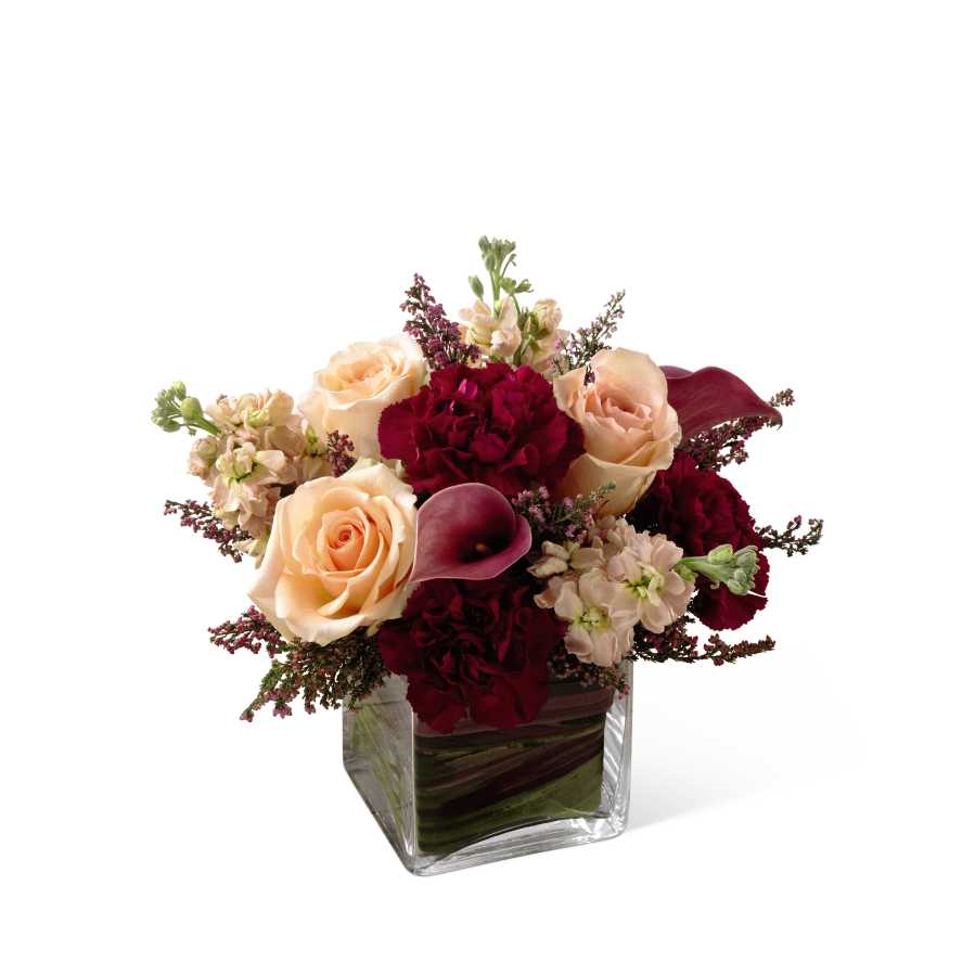 The FTD Share My World Bouquet - The FTD Share My World Bouquet blooms with modern sophistication and elegance to bring your special recipient a truly exquisite gift. Peach roses, peach stock, burgundy mini carnations and plum mini calla lilies are simply fantastic accented with heather stems and seated in a clear glass cubed vase. Variegated ti leaves and red flax leaves are used to line the inside of the vase for an appealing look making this brilliant bouquet set to extend your warmest wishes and sweet affection with its blushing color and array of textures. GOOD bouquet includes 11 stems. Approx. 9âH x 11âW. BETTER bouquet includes 15 stems. Approx. 10âH x 12âW. BEST bouquet includes 21 stems. Approx. 12âH x 14âW.