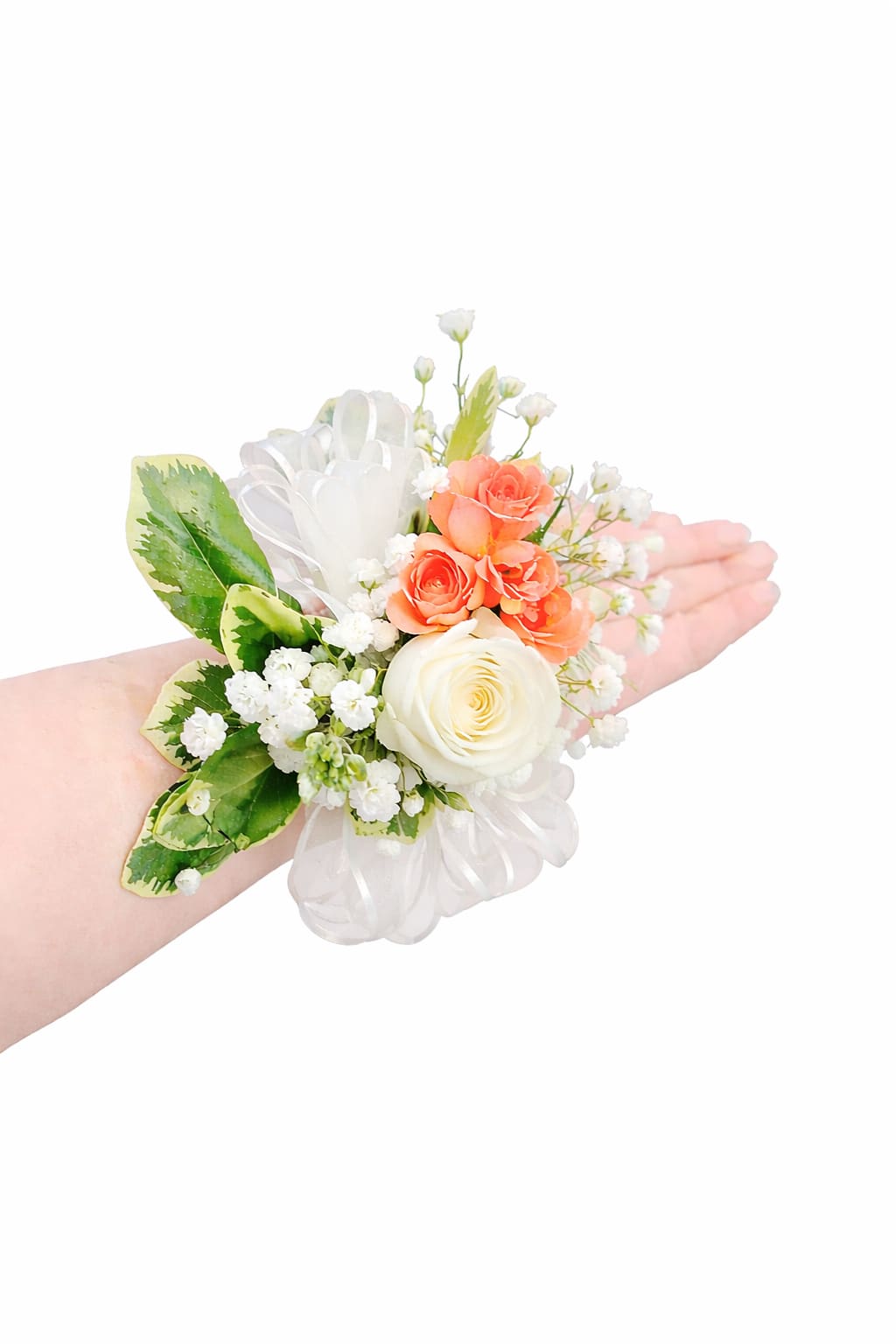 Peach spray rose and white rose wrist corsage with baby's breath and ribbon on a person's arm