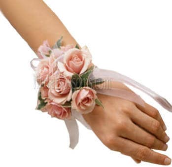 Wrist corsage of light pink roses with white ribbon on a person's hand