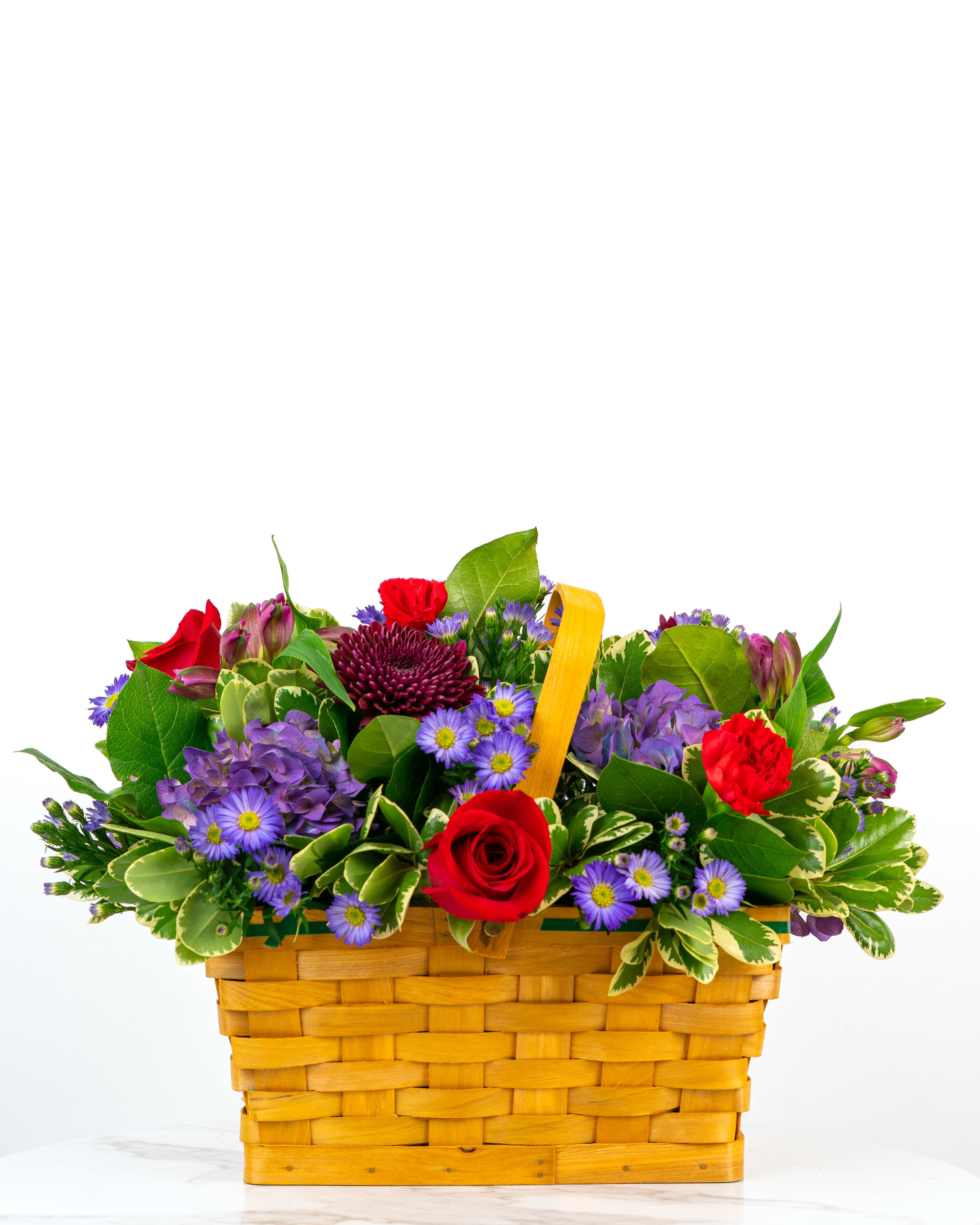 Mixed bouquet in a woven basket with red and purple flowers