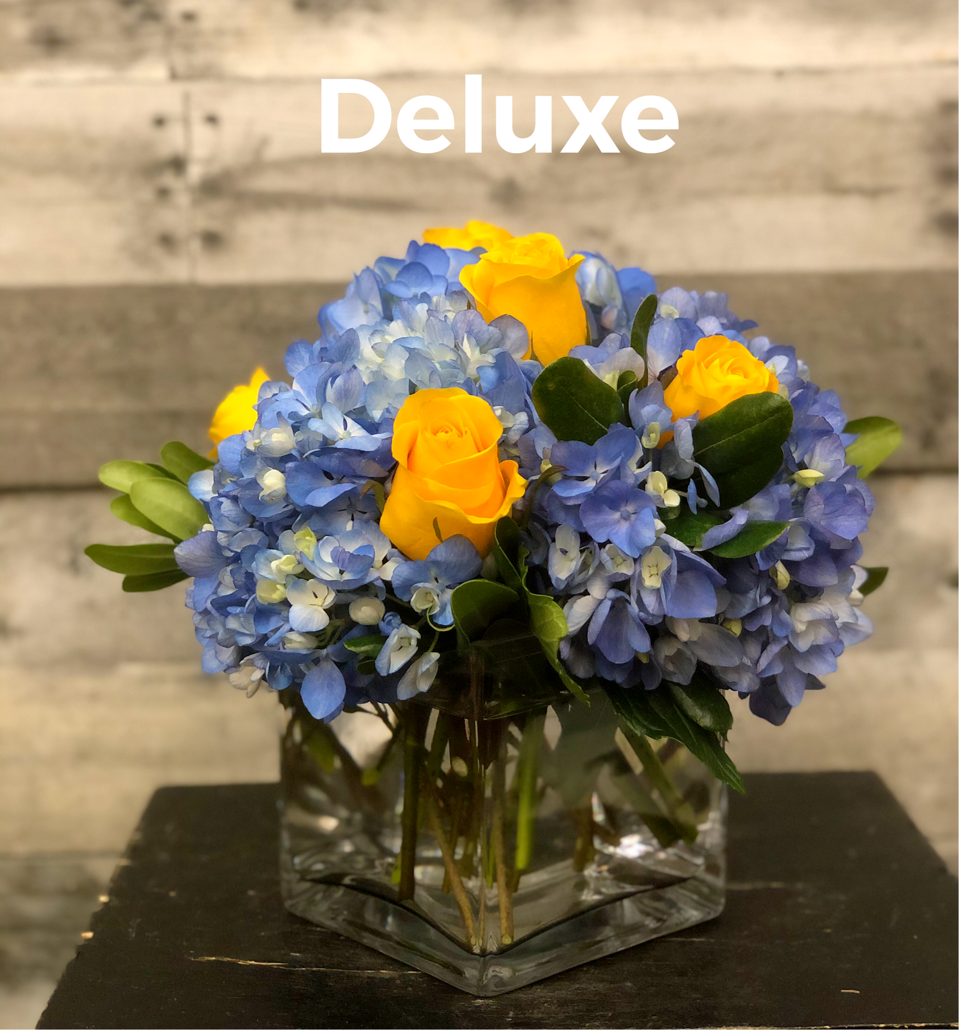 Spring Song - Glass cube vase with blue hydrangea and yellow roses.  Due to product availability, container may vary.