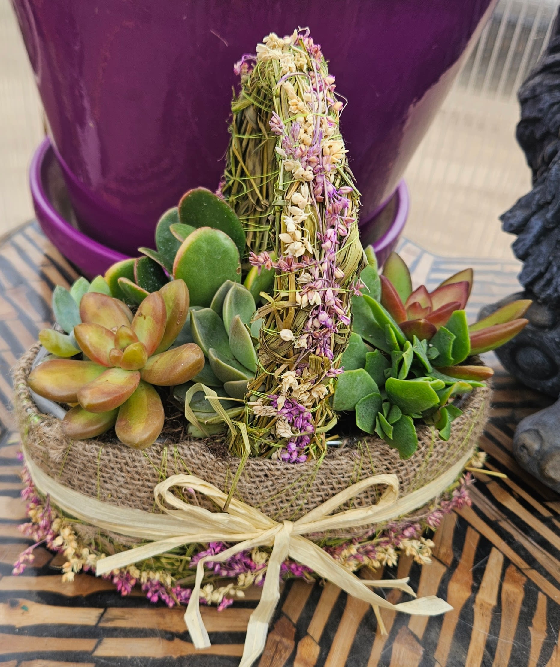 Wild Prairie Succulent Garden - Bring a grounded, organic touch to any space with this handcrafted succulent garden, designed by an experienced Omaha floral team. This arrangement features a curated mix of lush, long-lasting succulents accented with a natural dried herb bundle centerpiece for a rustic, elevated look.  Each piece is thoughtfully arranged in a textured container with natural accents, making it both modern and earthy. No two are exactly alike — every design is created fresh in our Omaha studio.  