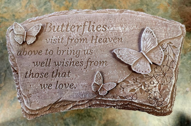 Stone plaque with raised butterflies and a memorial quote engraved on the surface