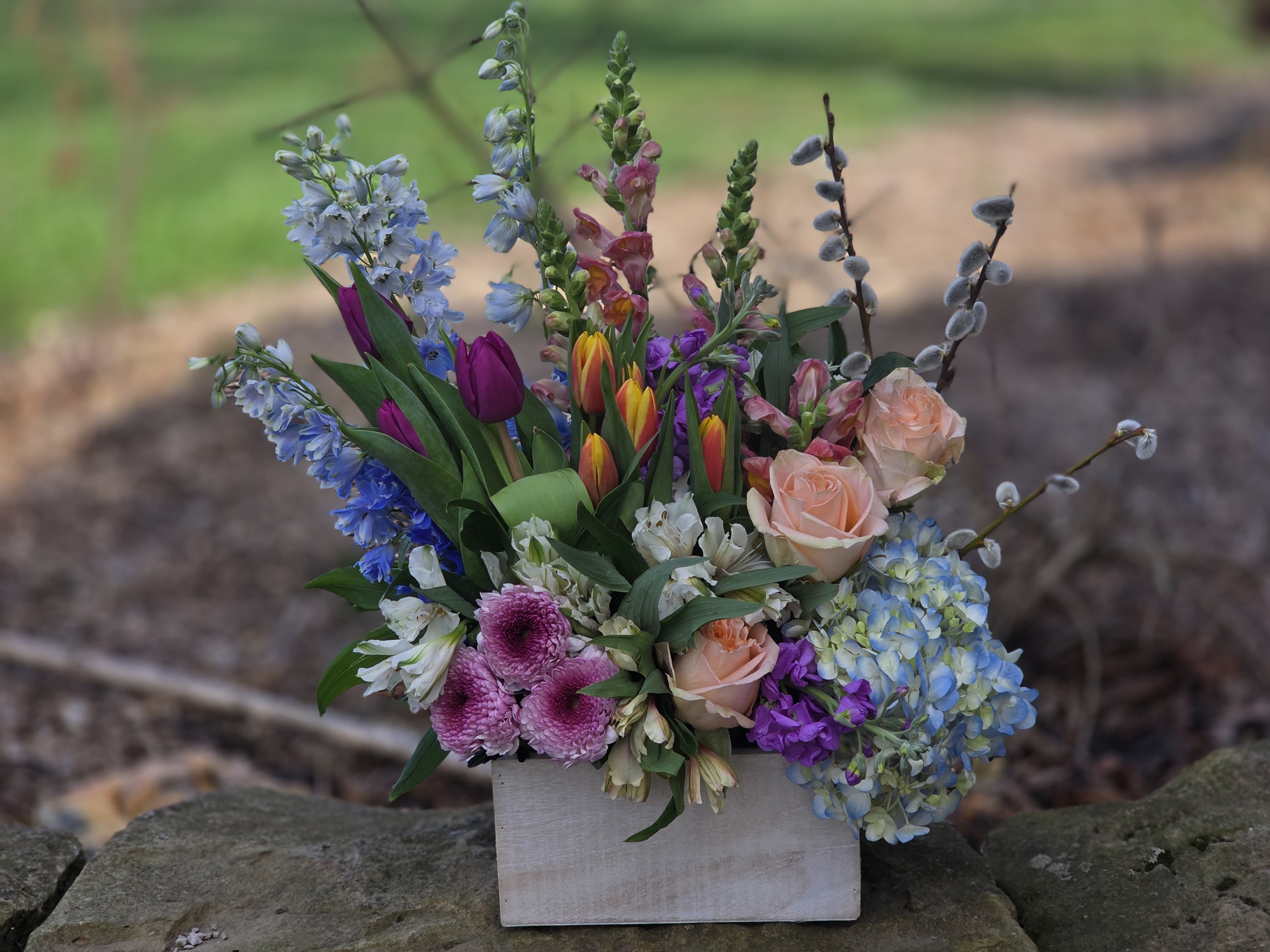 Spring Garden of Joy - A white box overflowing with colorful spring blooms! Filled with hydrangea, delphinium, tulips, snapdragons - this arrangement will bring joy to everyone, filling the room with spring joy!