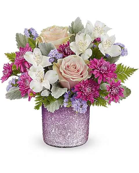 Short arrangement of pink roses, white alstroemeria and purple mums in a textured lavender glass vase