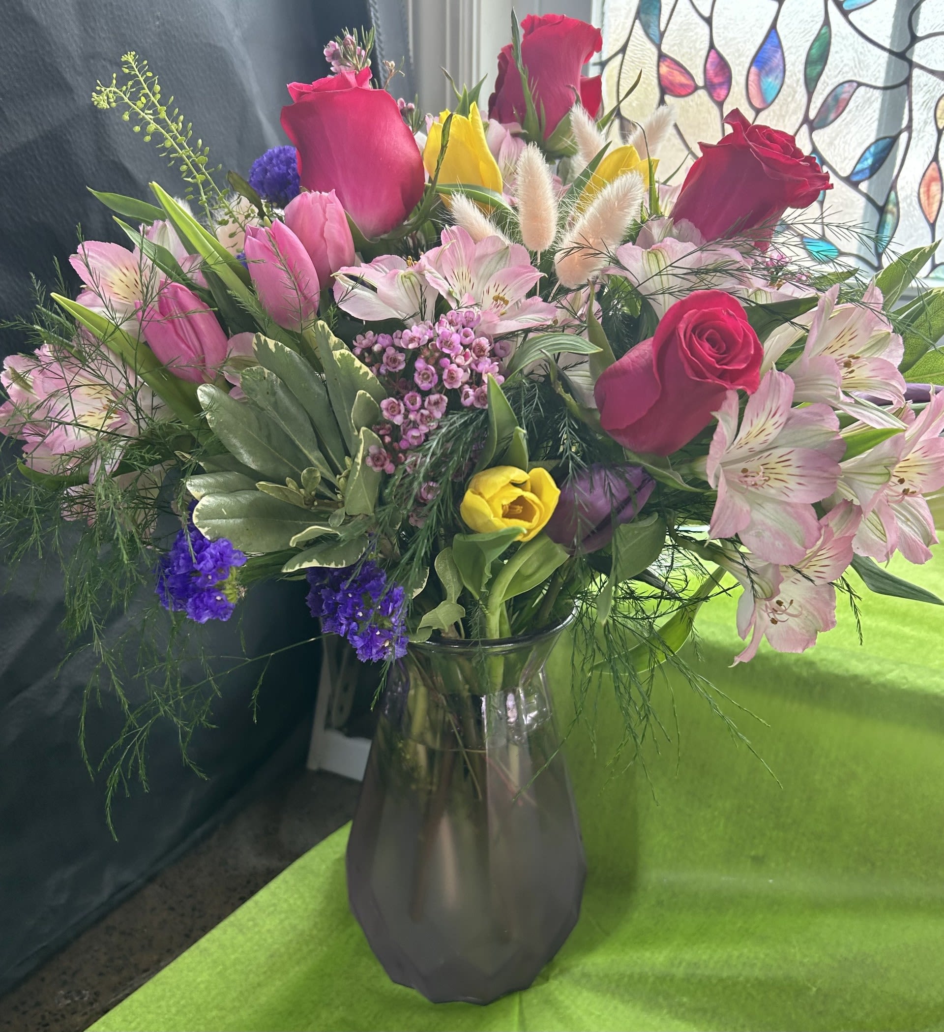 Easter Celebration - Festive lavender keepsake vase with Roses, Alstroemeria, tulips, wax flower and statice.  Colorful in celebration of Easter.