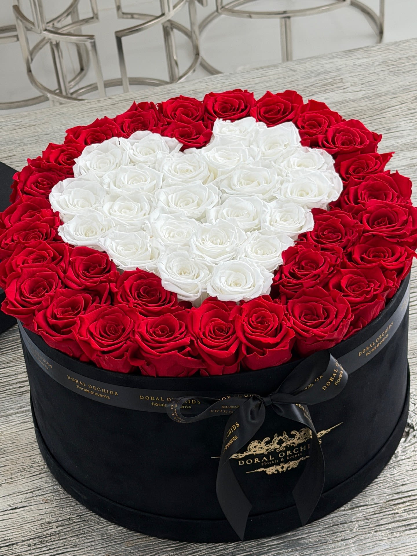 Red &amp; White Heart Preserved Roses Luxury Velvet Box - A bold and romantic statement, this luxury velvet box features 50+ premium preserved roses arranged in a stunning red and white heart design. The vibrant red roses create a rich outer frame, while soft white roses form a perfect heart at the center, symbolizing love and elegance. Each rose is preserved to maintain its natural beauty and softness for years, making this arrangement a timeless gift. Finished in a sleek black velvet box with signature detailing, it’s perfect for anniversaries, special occasions, or unforgettable gestures.