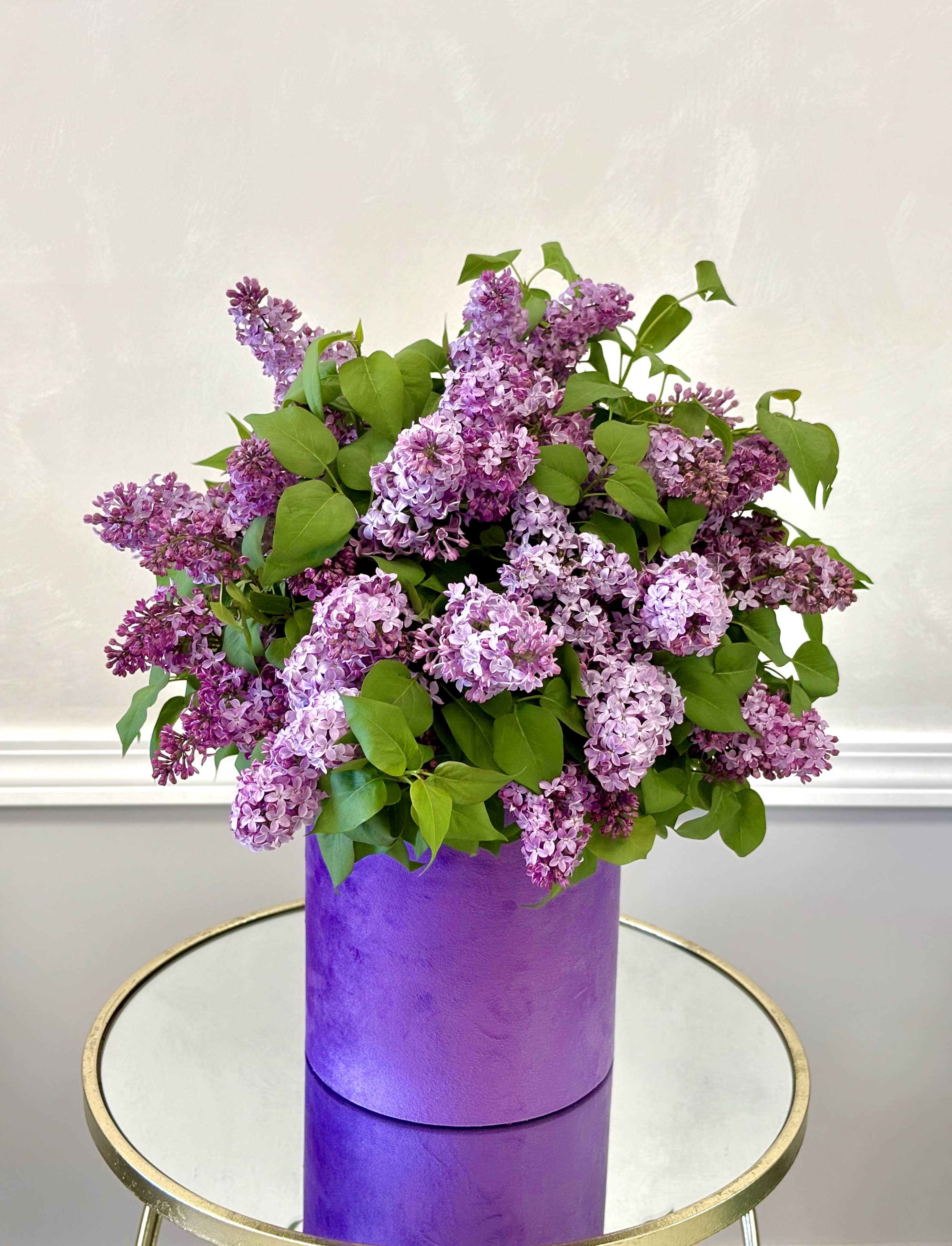 Lilac Hat Box By VLM Flowers - Lilac is a fragrant spring flower with soft purple blooms and lush green leaves, perfect for adding a fresh, elegant touch to any space.