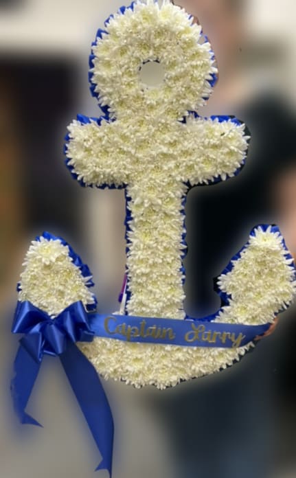 Anchor Tribute Spray - This custom sympathy arrangement features a beautifully designed anchor shape, approximately 28+ inches tall. Symbolizing strength, hope, and steadfastness, the anchor offers a meaningful tribute to honor a loved one.  Carefully crafted using fresh flowers, this piece creates a striking and thoughtful display suitable for funeral services or memorials.  If you would like a script included on the ribbon, please note your request in the florist note section when placing your order.  For delivery, please enter the name of the deceased in the recipient field and include the correct date of the service to ensure proper timing and placement.