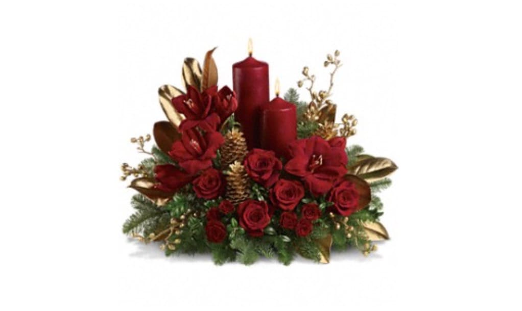 Candlelit Christmas - Premium red flowers are perfectly arranged with golden pinecones and holiday greenery.  Two pillar candles in a stunning shade of pomegranate are the perfect touch to light up the night