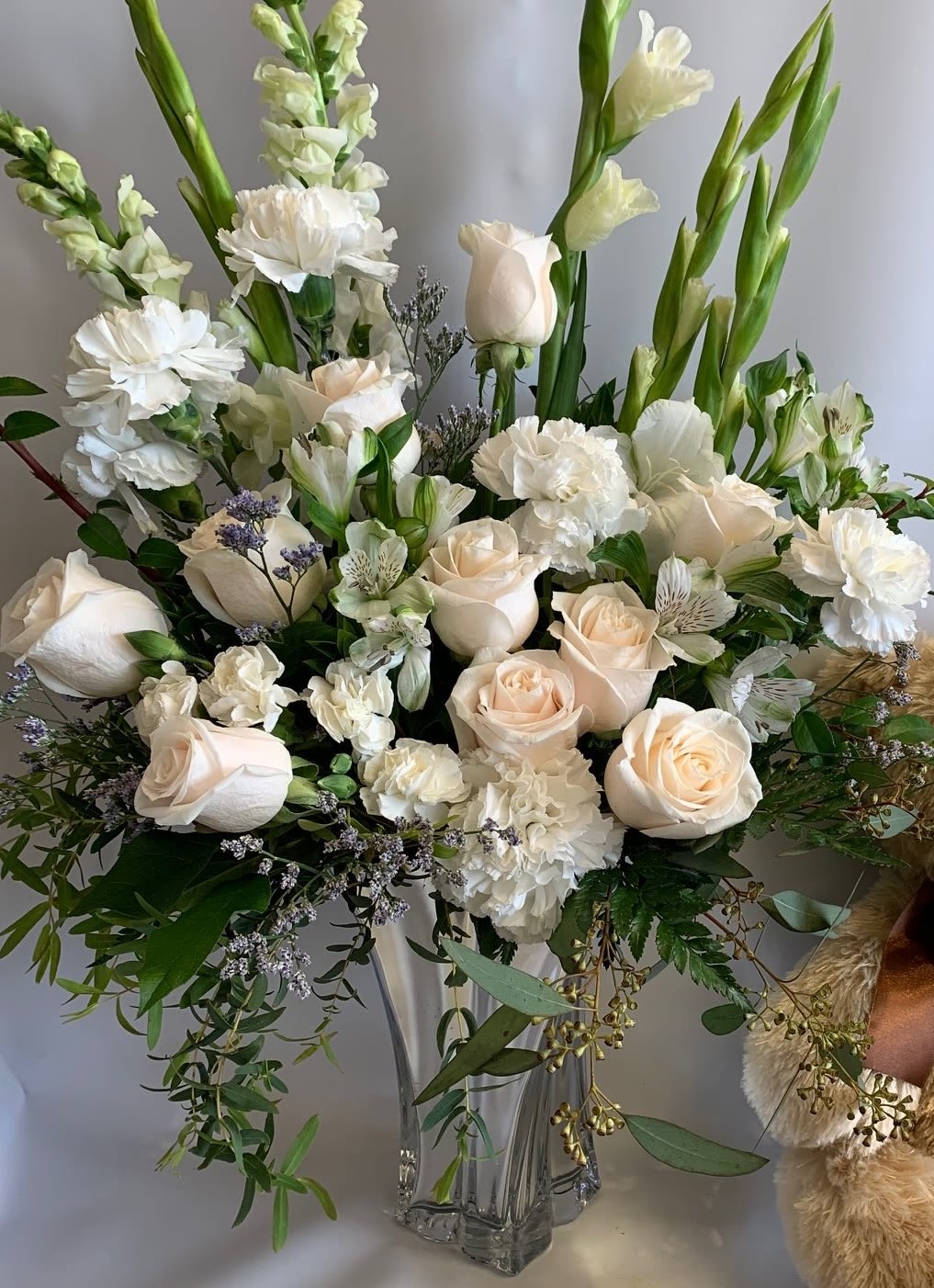 Floating On Air - Floating On Air is a creamy white cloud of 10 white roses, snapdragons, and other fluffy white blooms, arranged in a specialty glass vase. This all-white arrangement is the perfect symbol of purity and love.
