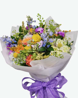 Wild and Whimsy Cellowrap - A sweet seasonal cello wrapped bouquet filled with fresh blooms in a soft spring palette and finished with a keepsake acrylic butterfly stake and a bow. This bouquet comes wrapped with a hidden water sponge to keep stems fresh for a few hours.  No vase included