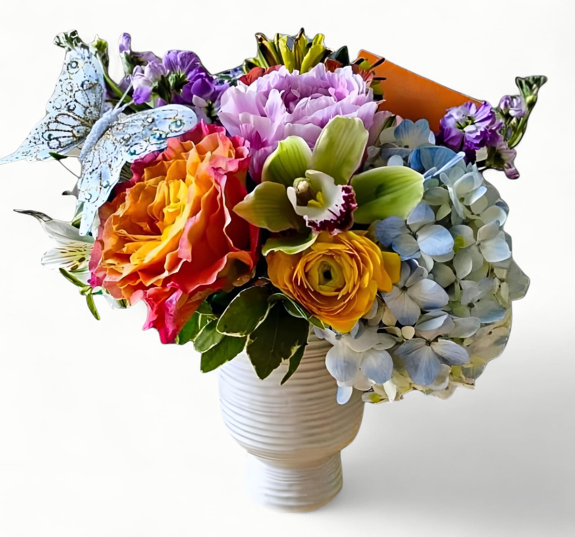 Bright mixed flower arrangement with roses, hydrangea, orchid, and butterfly pick in a white vase