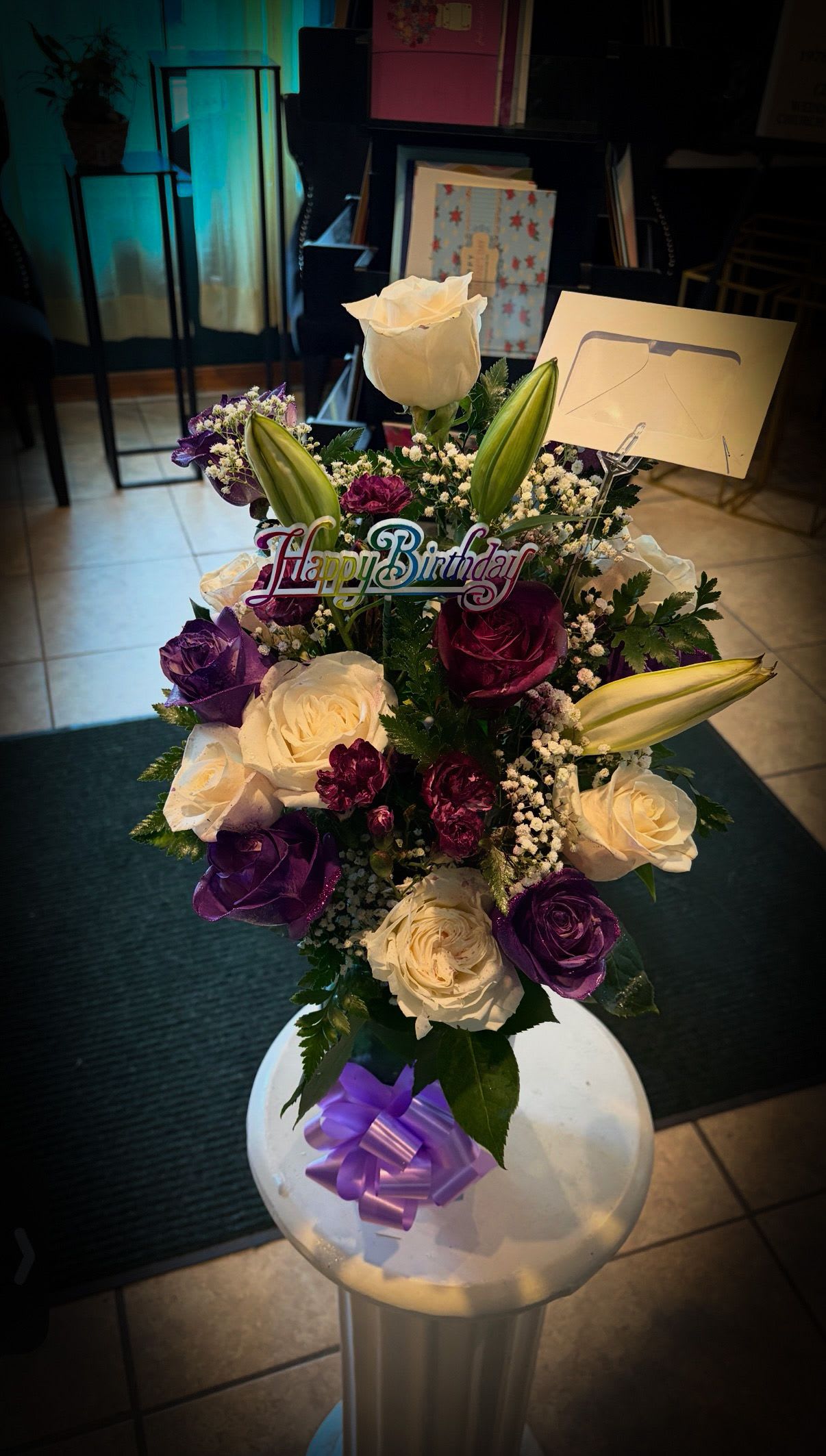 Royal Celebration Bouquet - A vibrant birthday arrangement with white and purple roses, lilies, and delicate accents, finished with a festive “Happy Birthday” pick and soft lavender bow.  