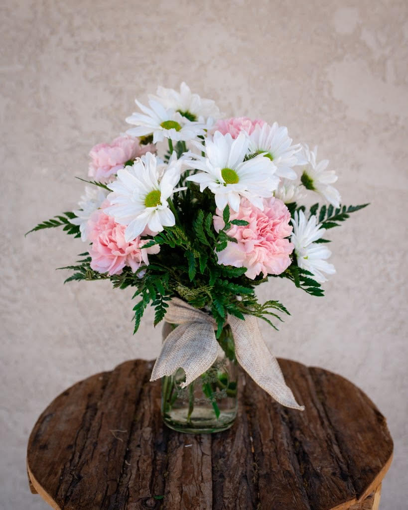 Daisy Pops - Who wouldn't love an adorable POP of cute daisy mums and sweet carnations? Perfectly sized for a desk or side table in a small mason jar. If you're looking for a specific color of carnations just let us know in the "special instructions" area of the order and we'll do our best to accommodate. Show your special someone that your thinking of them with a lasting POP of blooms! ***DURING MOTHERS DAY CARNATION COLOR MAY VARY, WILL BE PASTEL***