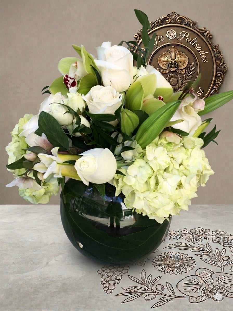 Love Infinity - A lush, elegant arrangement in soft white and green tones, featuring creamy roses, delicate calla lilies, and striking cymbidium orchids, complemented by full hydrangea and layered greenery. The design feels timeless and refined, with a serene palette and rich textures arranged in a polished, modern vase.