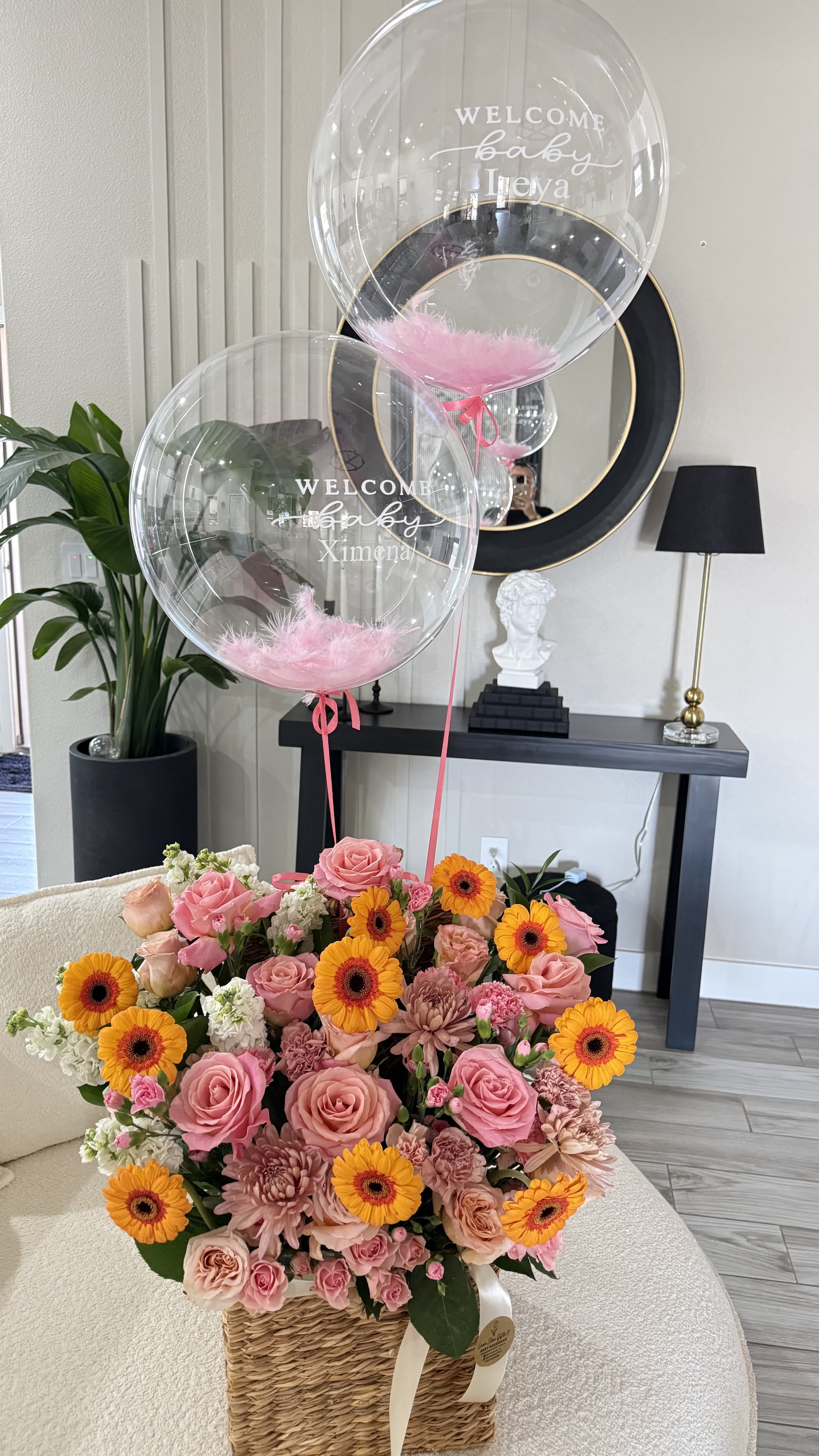 Welcome Baby Luxury Basket - Celebrate the arrival of a precious new baby with our elegant Welcome Baby Luxury Basket.  This beautiful arrangement features a fresh mix of premium roses, vibrant gerbera daisies, soft chrysanthemums, and delicate filler flowers, artfully designed in a charming woven basket. It is paired with two stunning personalized bubble balloons, creating a memorable and joyful gift for this special moment.   Each balloon is customized with the baby’s name for a unique and meaningful touch.   Handcrafted with love by Lone Star Gifts  Available for delivery in Midland, Odessa &amp; Gardendale  Same-day delivery available (order early