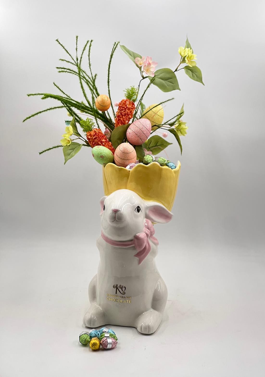 Royal Easter Bunny Chocolate Crown - A whimsical and eye-catching Easter centerpiece, this charming ceramic bunny features a crown-like top filled with decorative eggs, fresh greenery, and delicate spring accents. Nestled inside are premium, real egg-shaped chocolates, adding a delightful and indulgent surprise to this playful design. Soft pastel tones and vibrant textures come together to create a festive yet elegant arrangement—perfect as a unique Easter gift or a joyful seasonal décor piece.