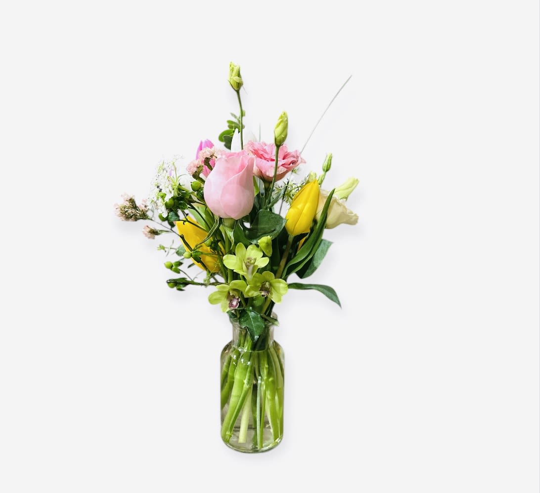 Tall mixed bouquet of pink and yellow flowers in a clear glass vase.