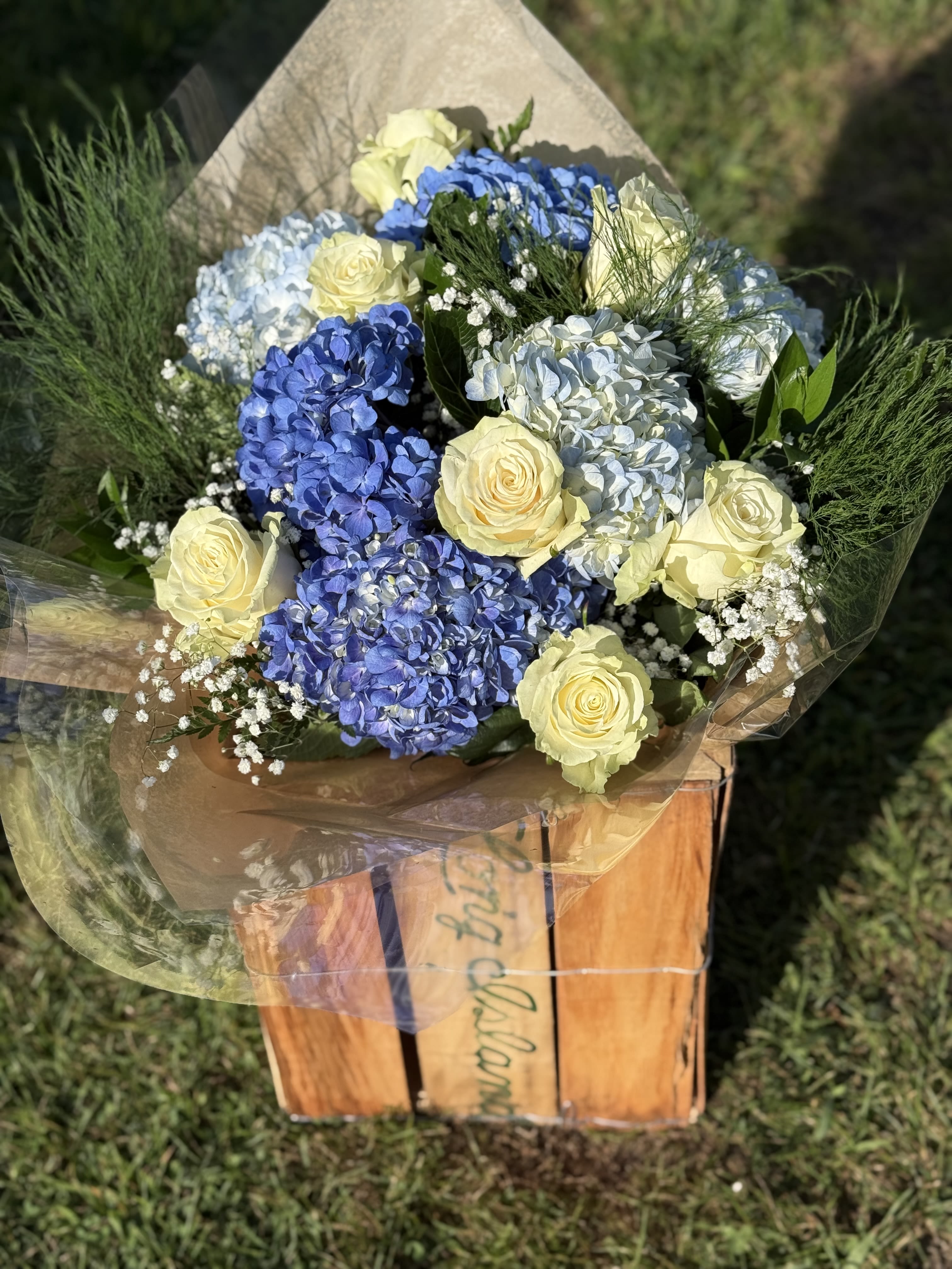Blue Skies hand wrapped Bouquet - **Blue Skies** – A hand wrapped serene blend of soft white roses, vibrant blue and pastel hydrangeas, and delicate sprigs of baby’s breath. This fresh, airy arrangement evokes the calm beauty of a clear summer sky, making it perfect for brightening any space or occasion.   