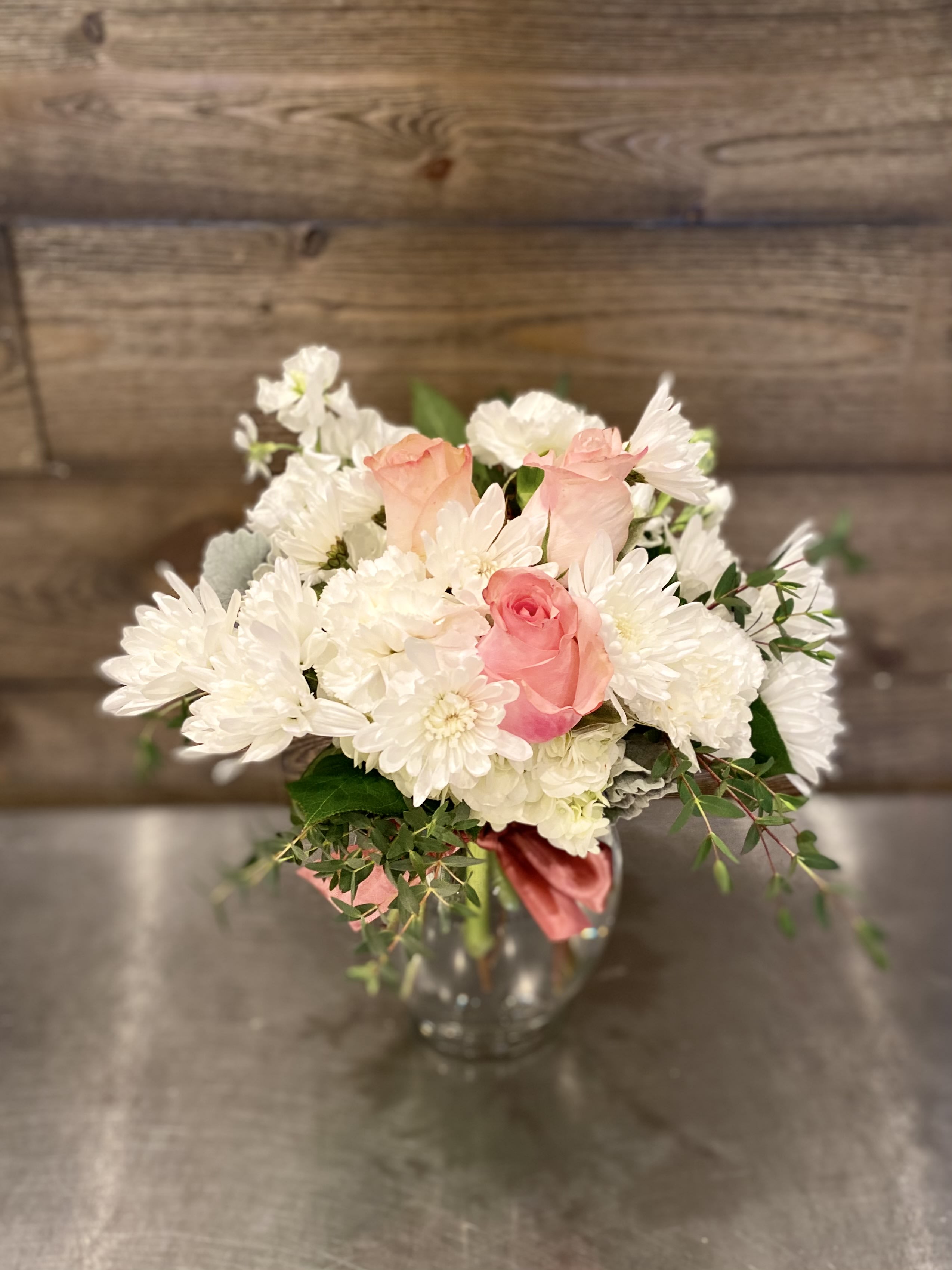 Pink roses and white daisies arranged in a clear glass vase