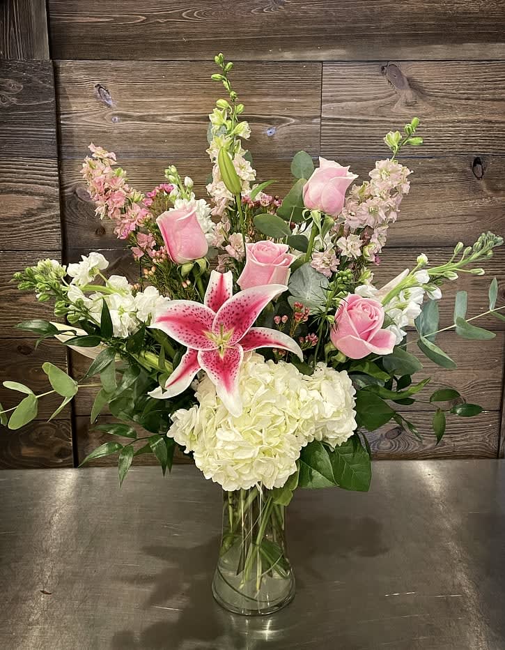Pink roses and a pink stargazer lily in a glass vase