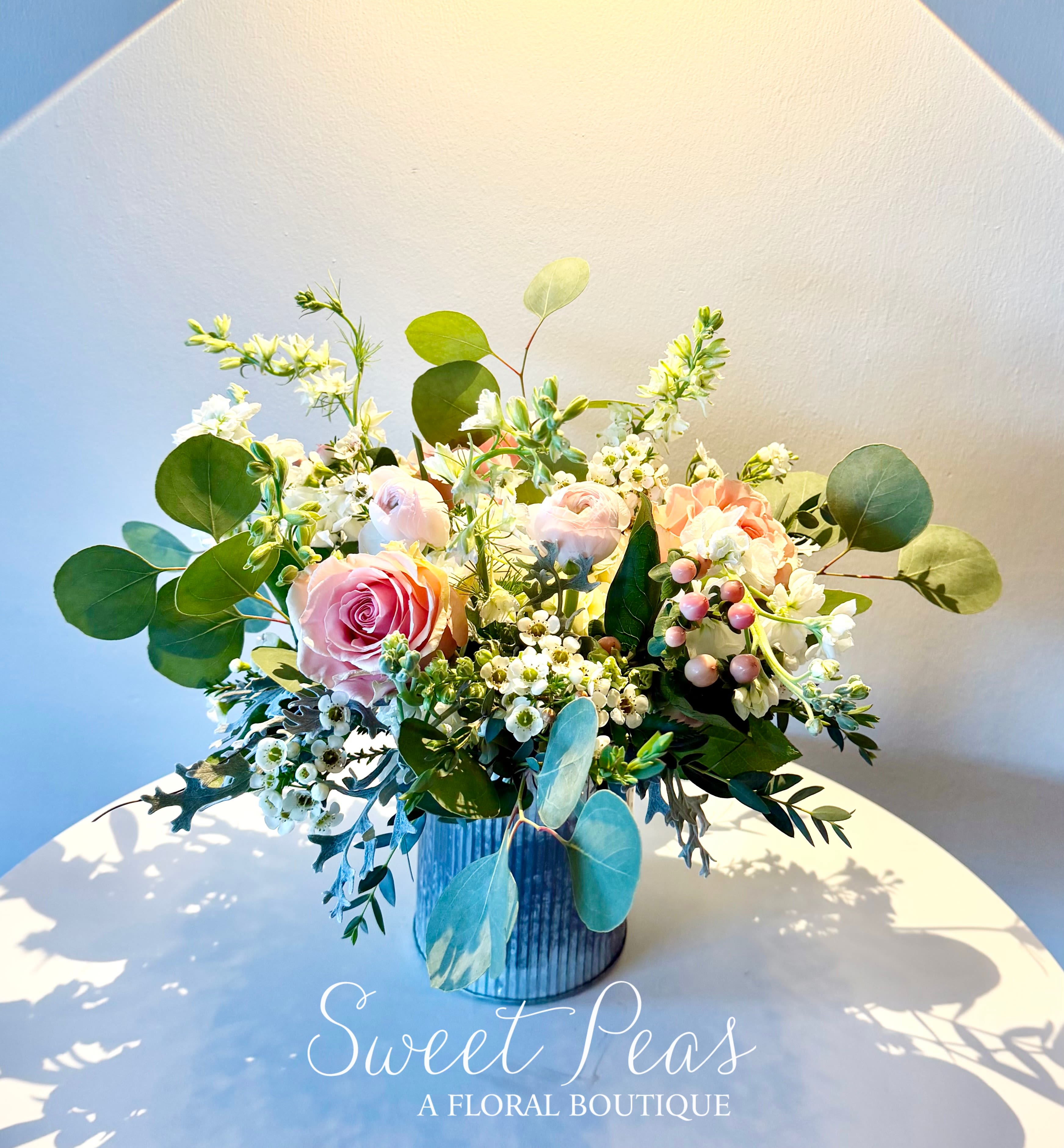 Pink roses and white blossoms arranged in a blue vase