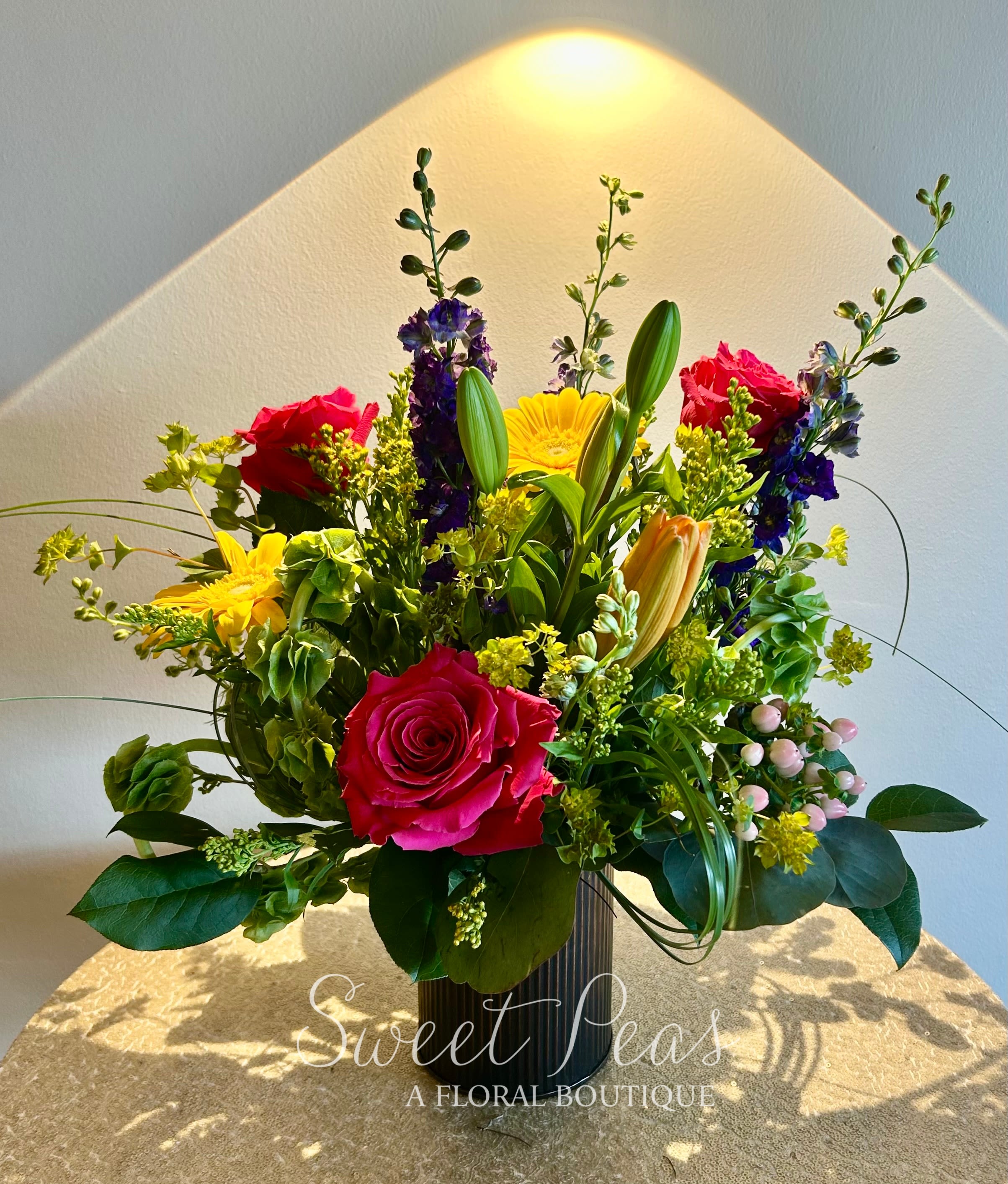 Mixed bouquet with pink roses, yellow daisies, and lilies in a vase