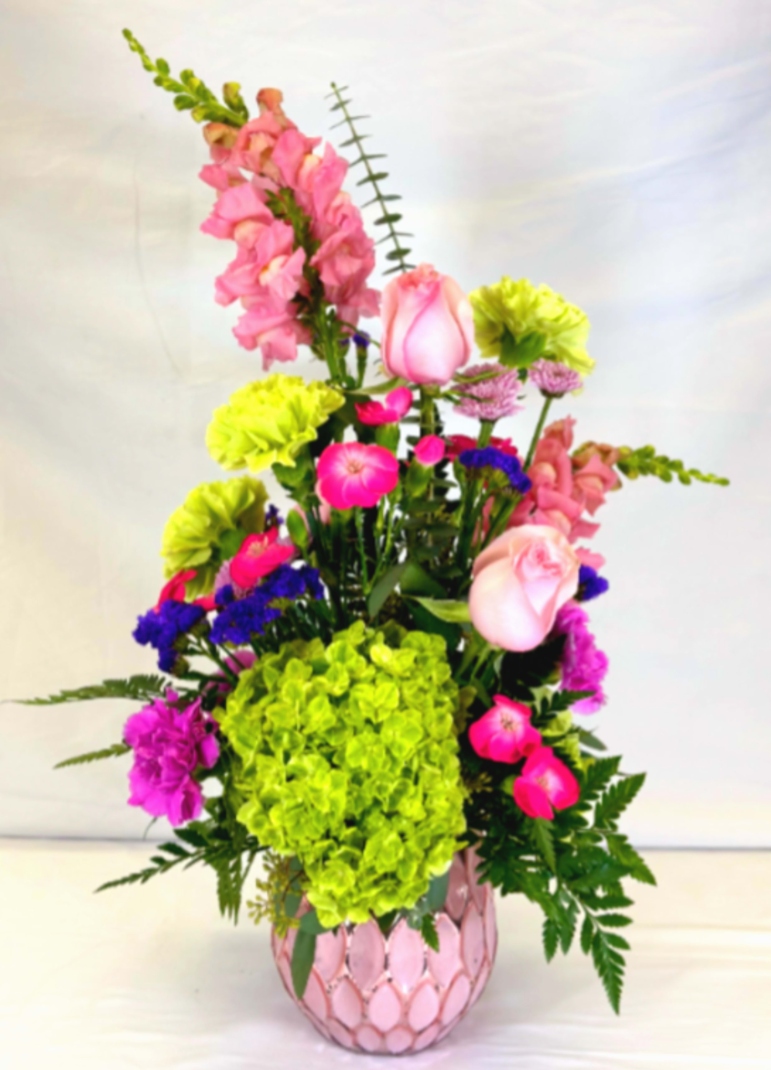 Wow Factor - If you love pink, green, and fun flowers, this wonderful design features it all , set off by pops of green hydrangeas and purple Statice with brightly colored pink blooms. This Leary's Flowers exclusive arrangement comes in a beautiful faceted pink mercury glass vase that will be cherished. This would brighten any day and would make a delightful gift for Mother's Day, Easter, a birthday, or any occasion when someone wants to be experience flowers with a wow factor.  If the featured flowers are unavailable we will design your arrangement using the freshest seasonal blooms of equal or greater value