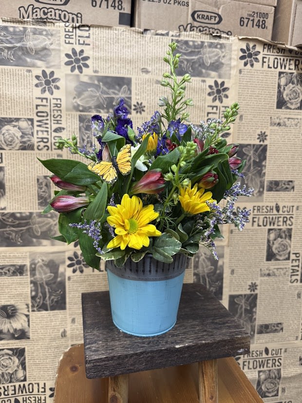 Mixed bouquet in a blue pot with yellow daisies and purple blooms